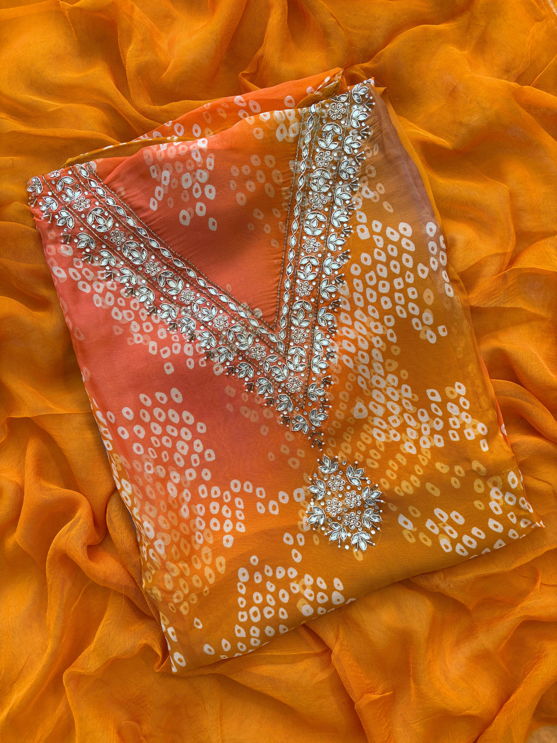 Orange organza bandhani suit with ombre effect and chiffon dupatta with lace border.