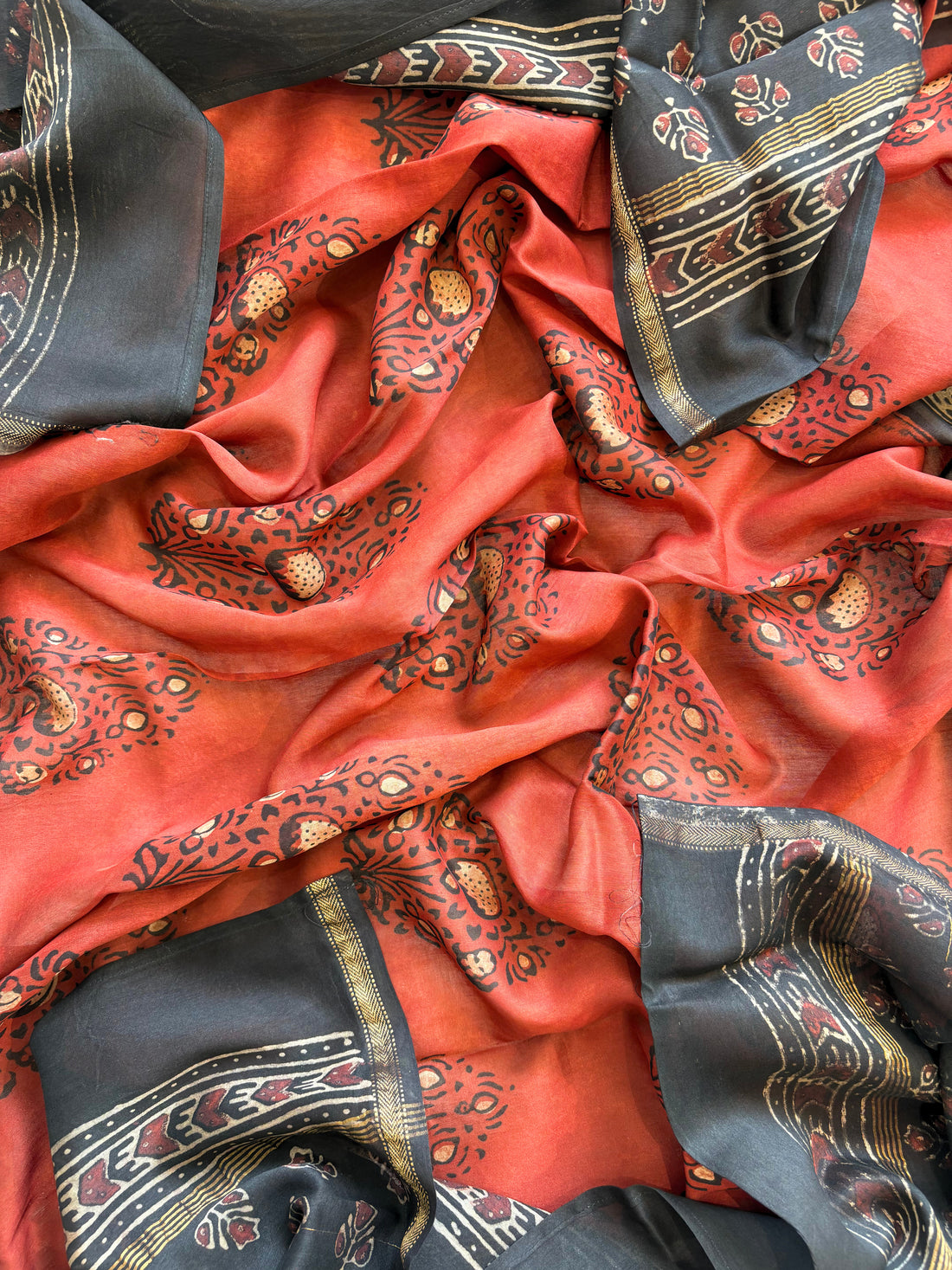 Black Maheshwari silk unstitched suit with hand block floral print, paired with rust dupatta featuring bold ethnic motifs – elegant festive ethnic wear
