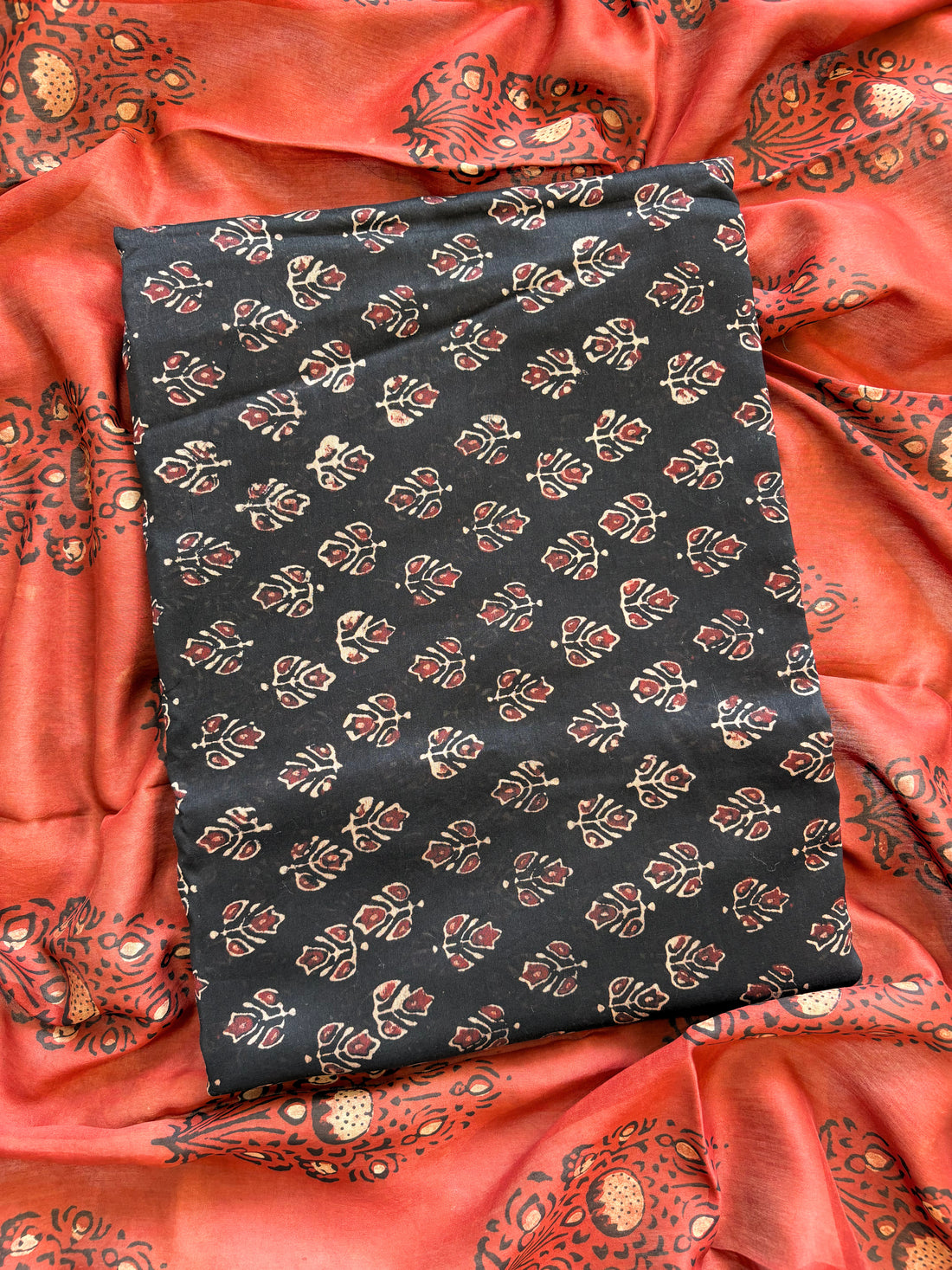 Black Maheshwari silk unstitched suit with hand block floral print, paired with rust dupatta featuring bold ethnic motifs – elegant festive ethnic wear