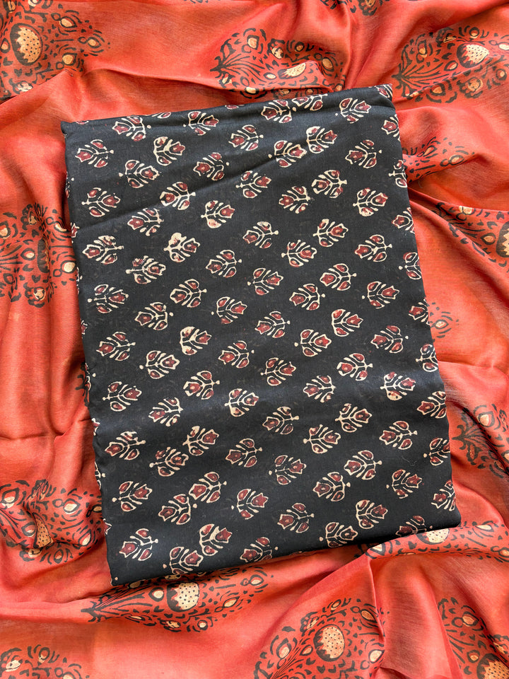 Black Maheshwari silk unstitched suit with hand block floral print, paired with rust dupatta featuring bold ethnic motifs – elegant festive ethnic wear