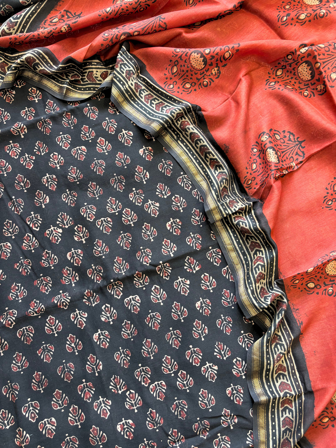 Black Maheshwari silk unstitched suit with hand block floral print, paired with rust dupatta featuring bold ethnic motifs – elegant festive ethnic wear