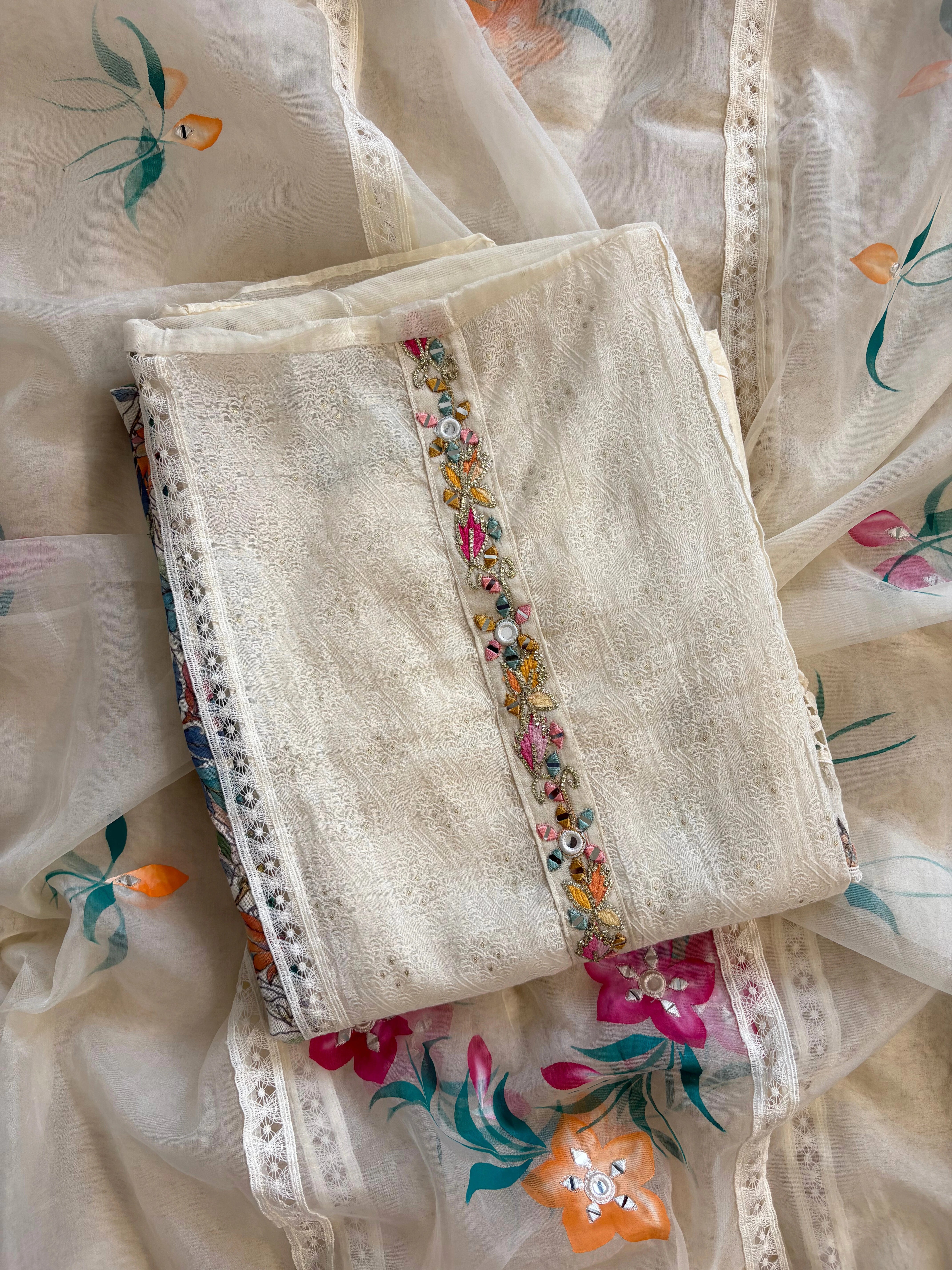 Ivory linen suit with embroidered detailing and hand-painted floral organza dupatta, finished with lace border – unstitched ethnic wear set