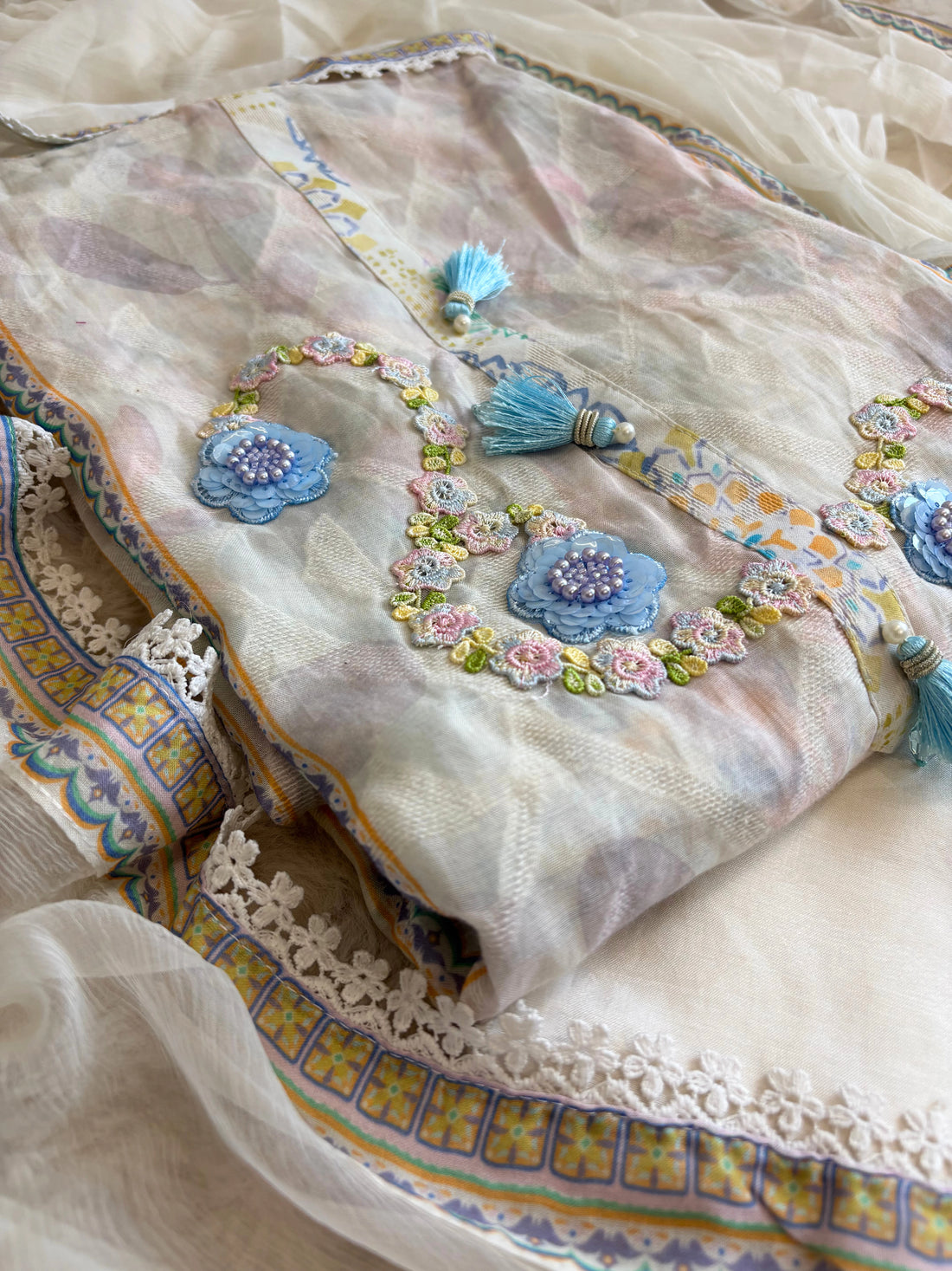 White cotton unstitched suit with embroidered neckline, lace detailing, and chiffon dupatta for summer festive wear.