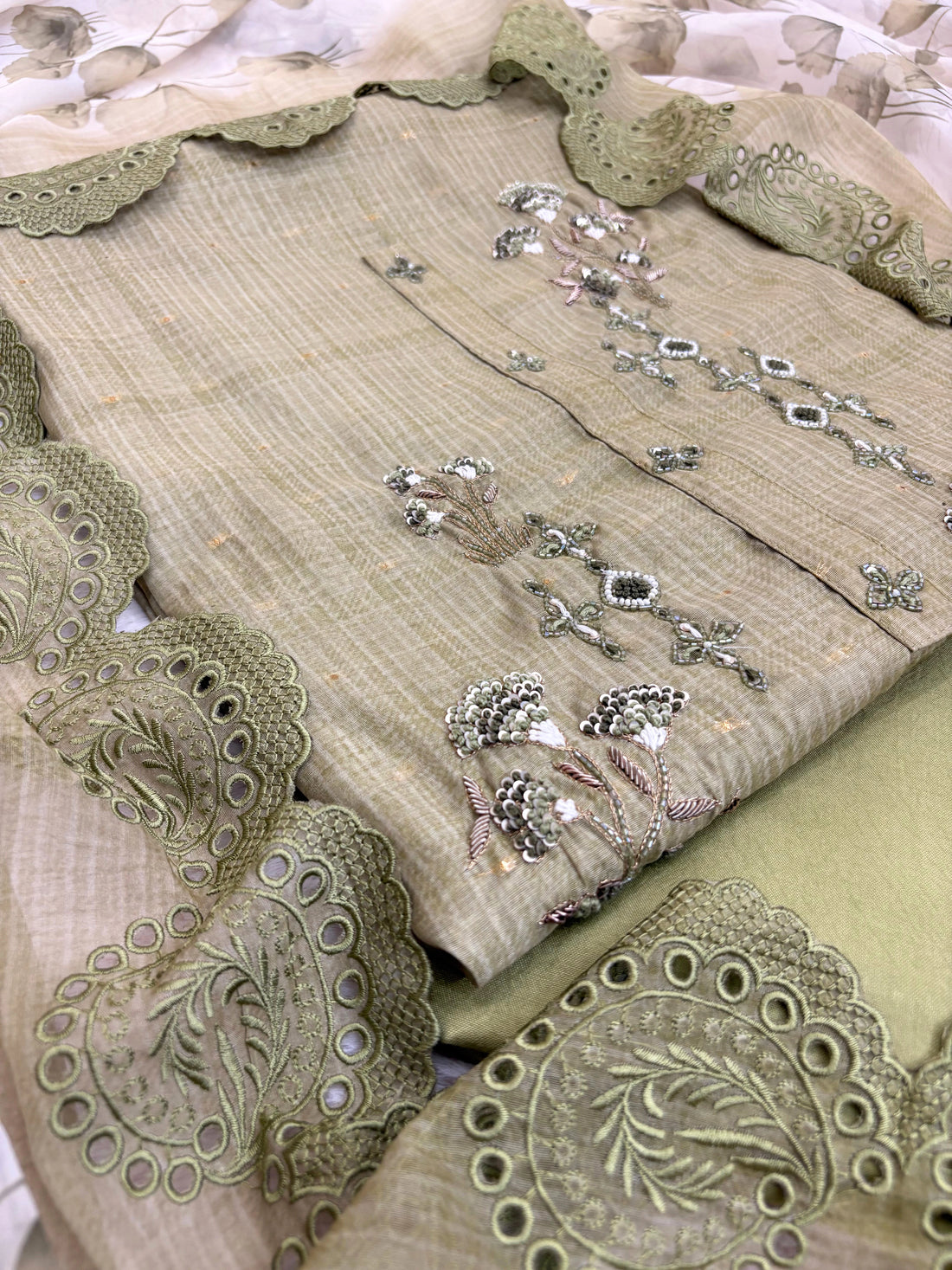 Olive green linen suit with floral threadwork, intricate lace detailing, paired with an organza dupatta with lace borders, ideal for weddings and special occasions.
