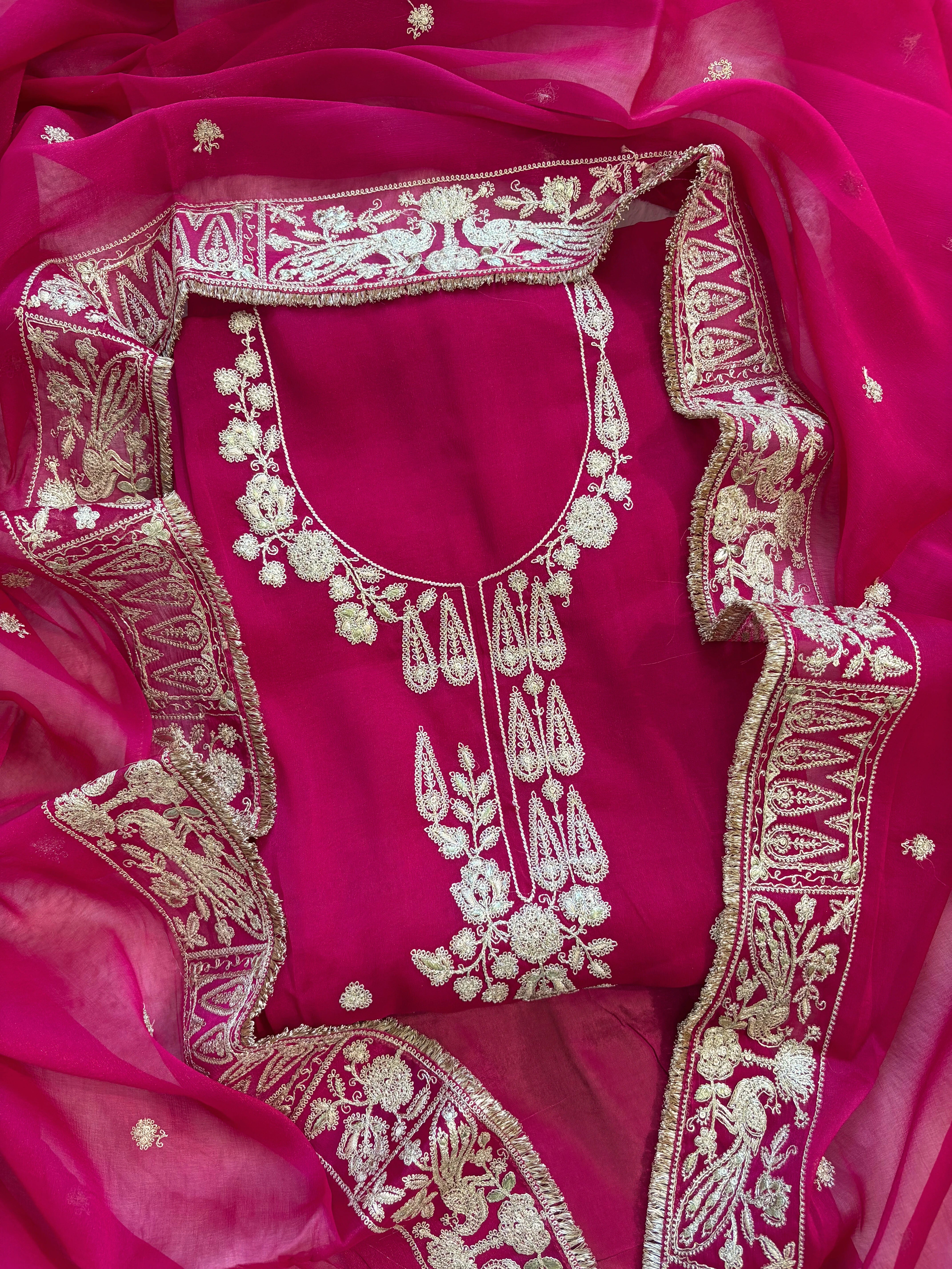 Hot pink organza unstitched suit with golden zari embroidery and embroidered dupatta, ideal for weddings and festive celebrations.