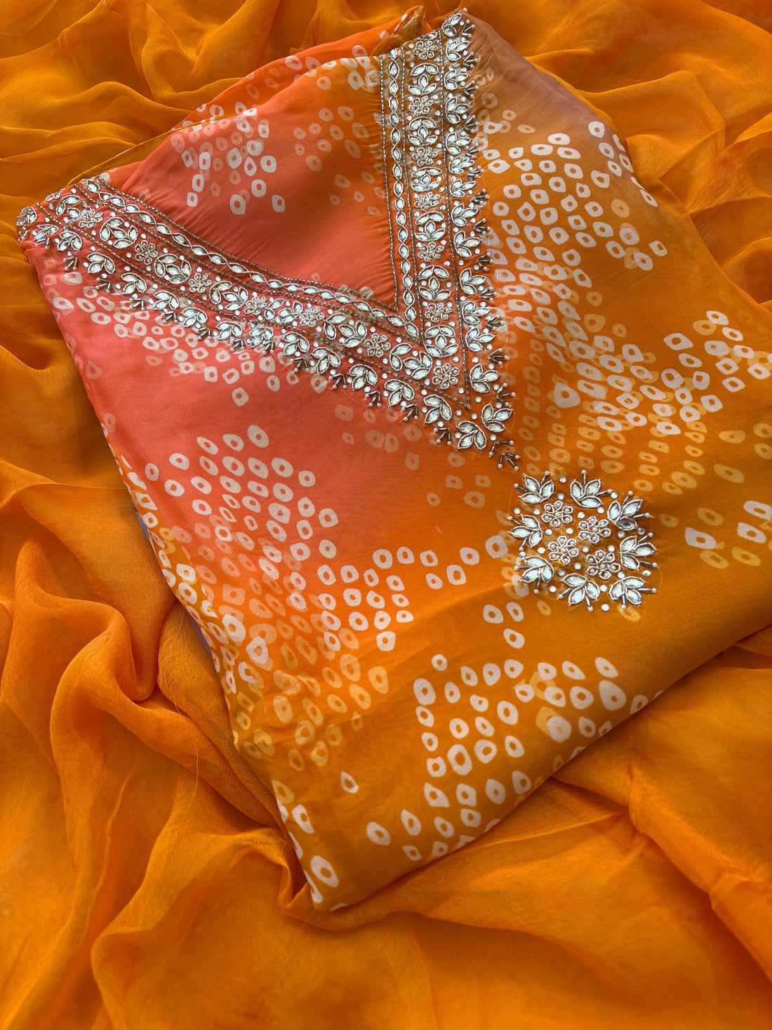 Orange organza bandhani suit with ombre effect and chiffon dupatta with lace border.