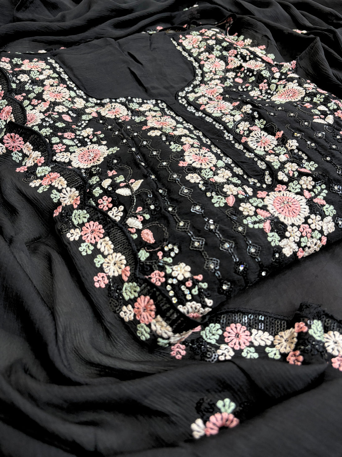 Black chiffon suit with intricate pastel floral embroidery, sequin accents, and a matching embroidered dupatta, ideal for weddings and festive occasions.