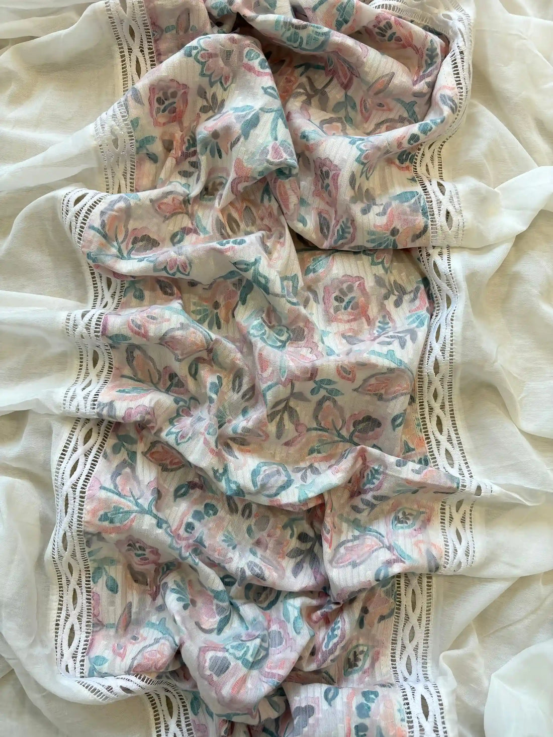 White cotton unstitched suit with embroidered neckline, lace detailing, and pastel floral organza dupatta for summer festive wear.