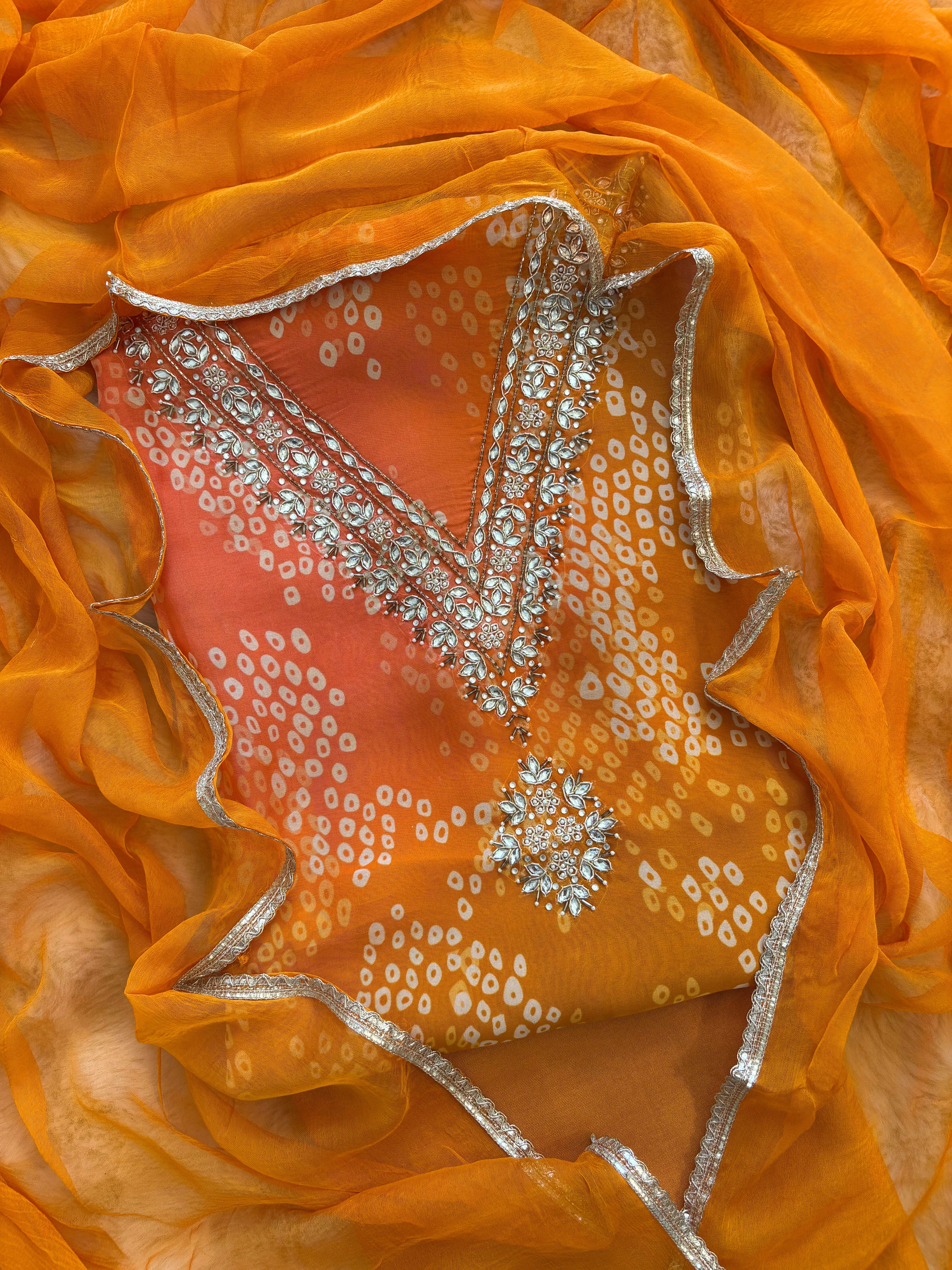 Orange organza bandhani suit with ombre effect and chiffon dupatta with lace border.