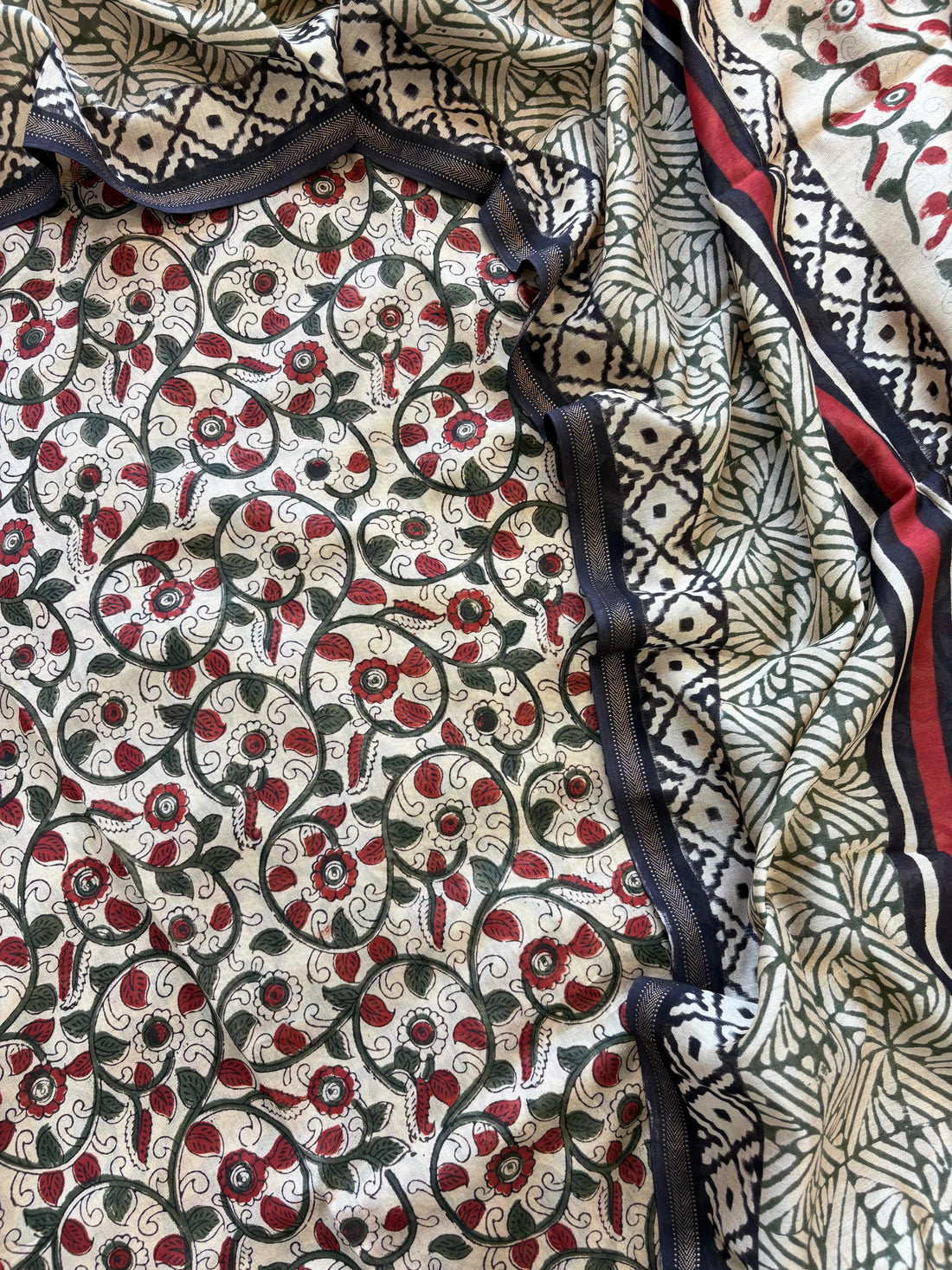 Maheshwari fabric suit with Kalamkari floral print in green, ivory, and maroon tones, featuring traditional hand-block designs and striped dupatta.