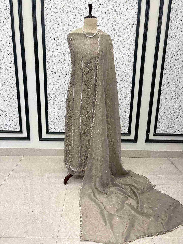 Taupe burberry tissue unstitched suit displayed on mannequin with heavy nalki and cutdana embroidery