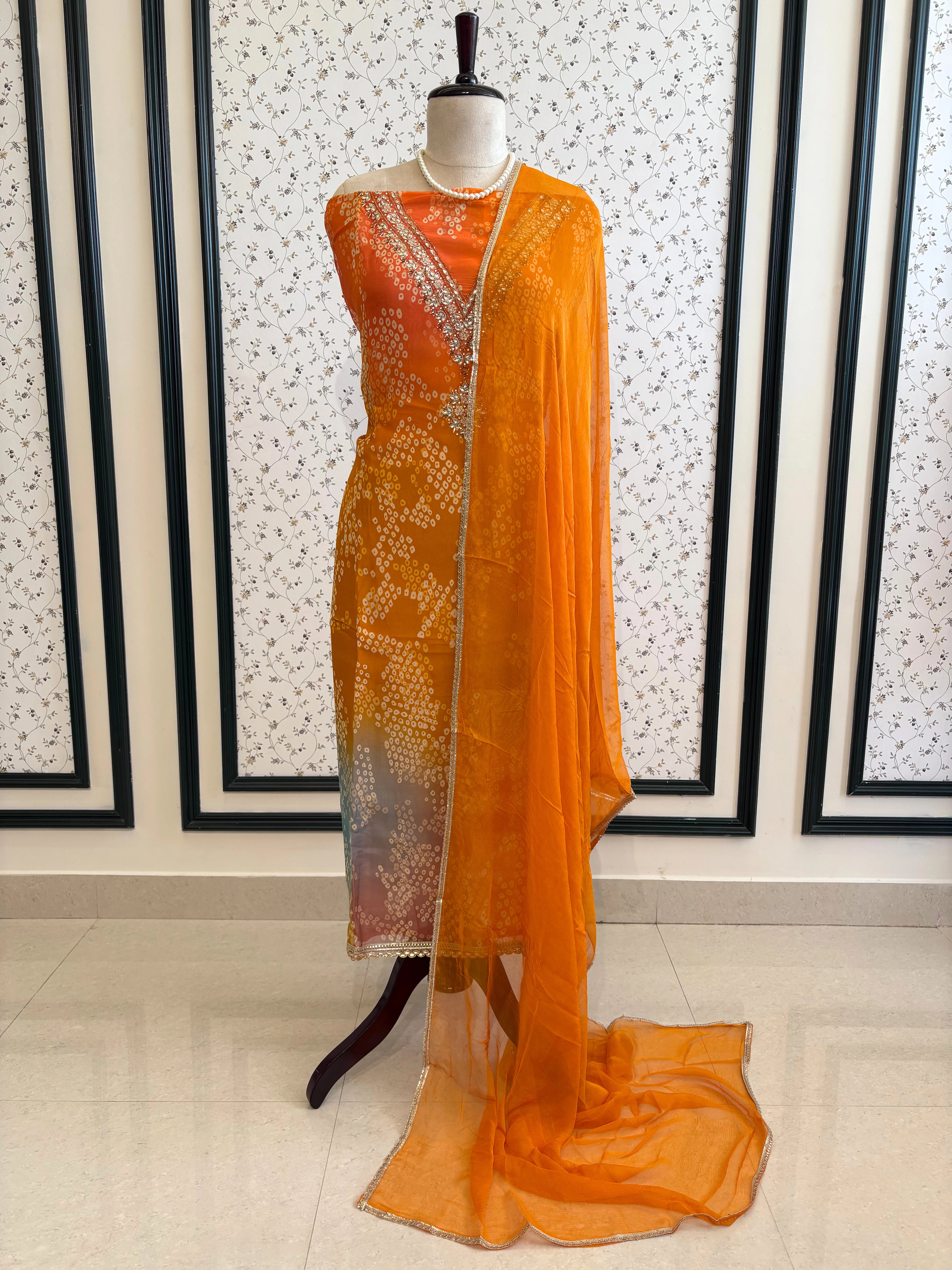 Orange organza bandhani suit with ombre effect and chiffon dupatta with lace border.
