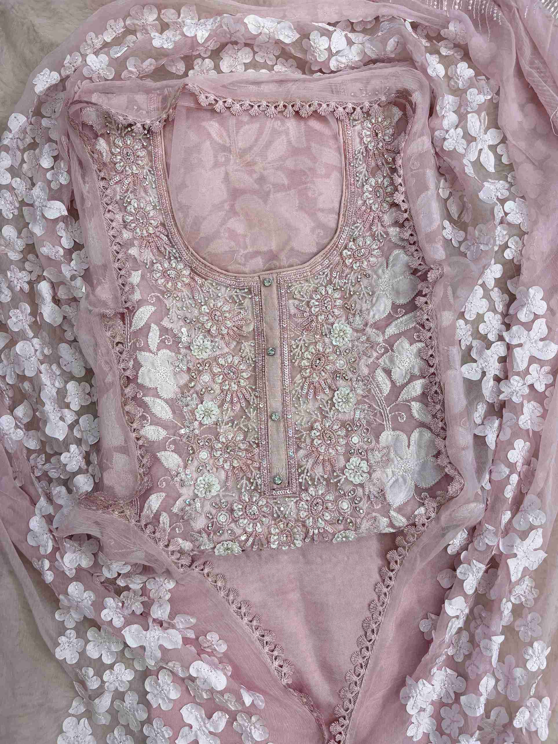 Close-up of all-over white floral applique work across the full body of baby pink organza shirt