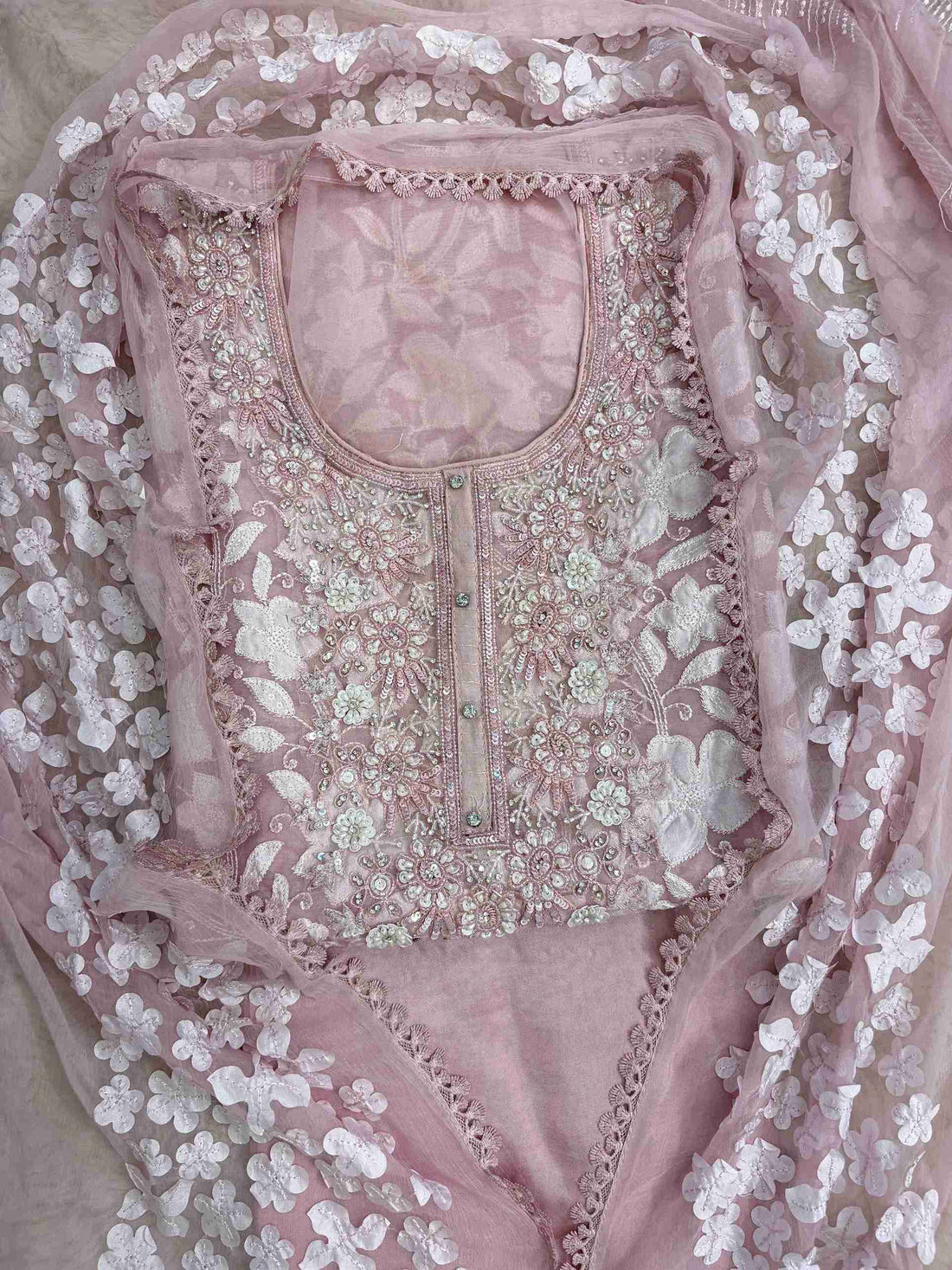 Close-up of all-over white floral applique work across the full body of baby pink organza shirt