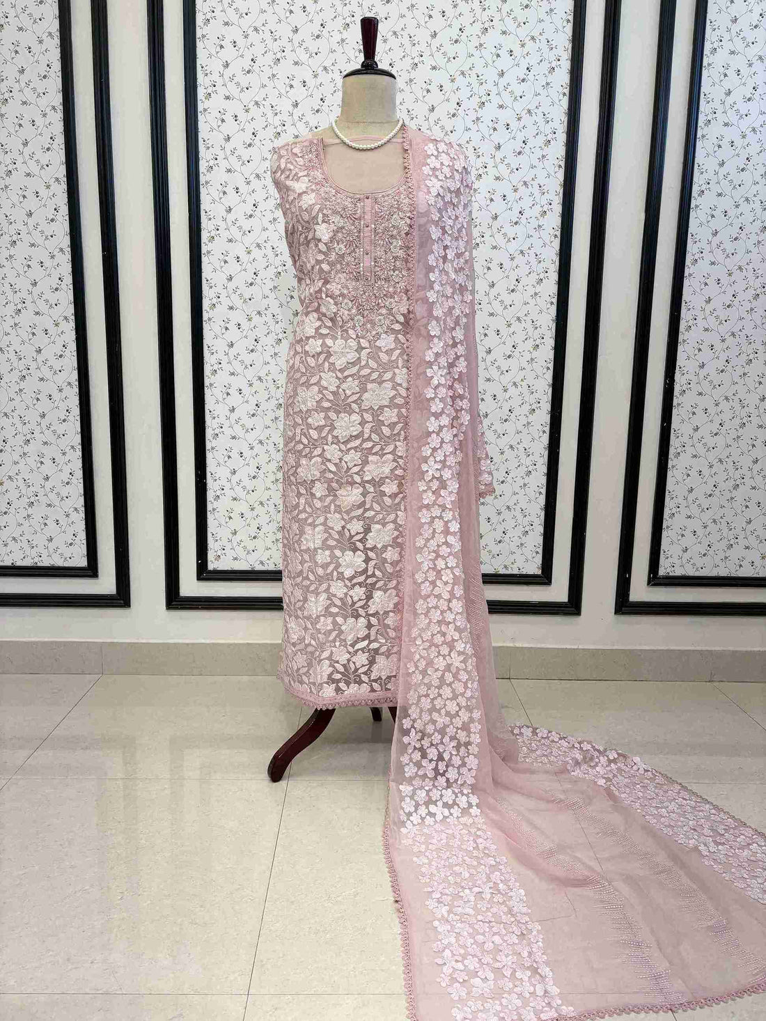 Baby pink organza unstitched suit full front view with white floral applique and four-sided lace chiffon dupatta draped on mannequin