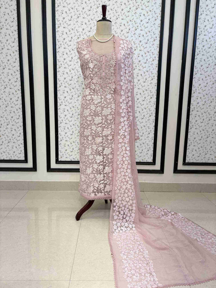 Baby pink organza unstitched suit full front view with white floral applique and four-sided lace chiffon dupatta draped on mannequin