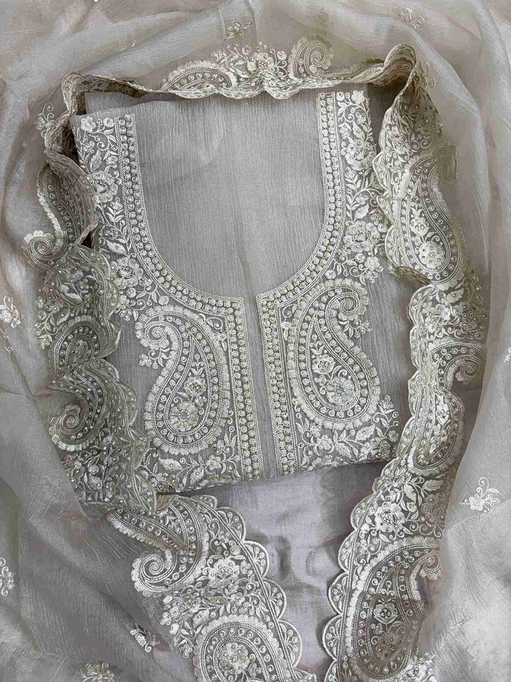 Close-up of intricate paisley neckline with cutdana, sequins, and pearl embellishments on beige marble chiffon shirt