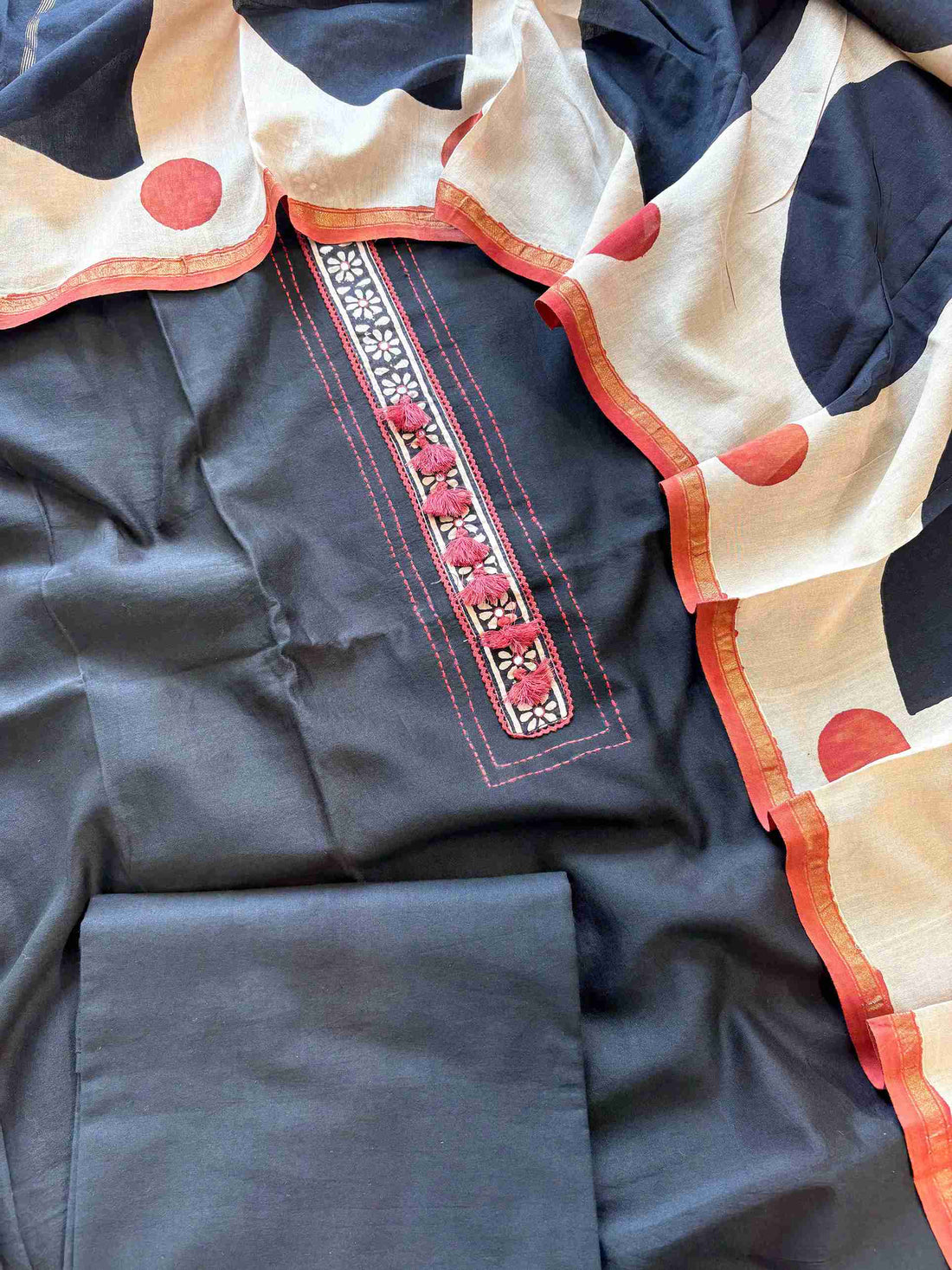 Red tassel and running-stitch detailing on black Maheshwari silk suit placket