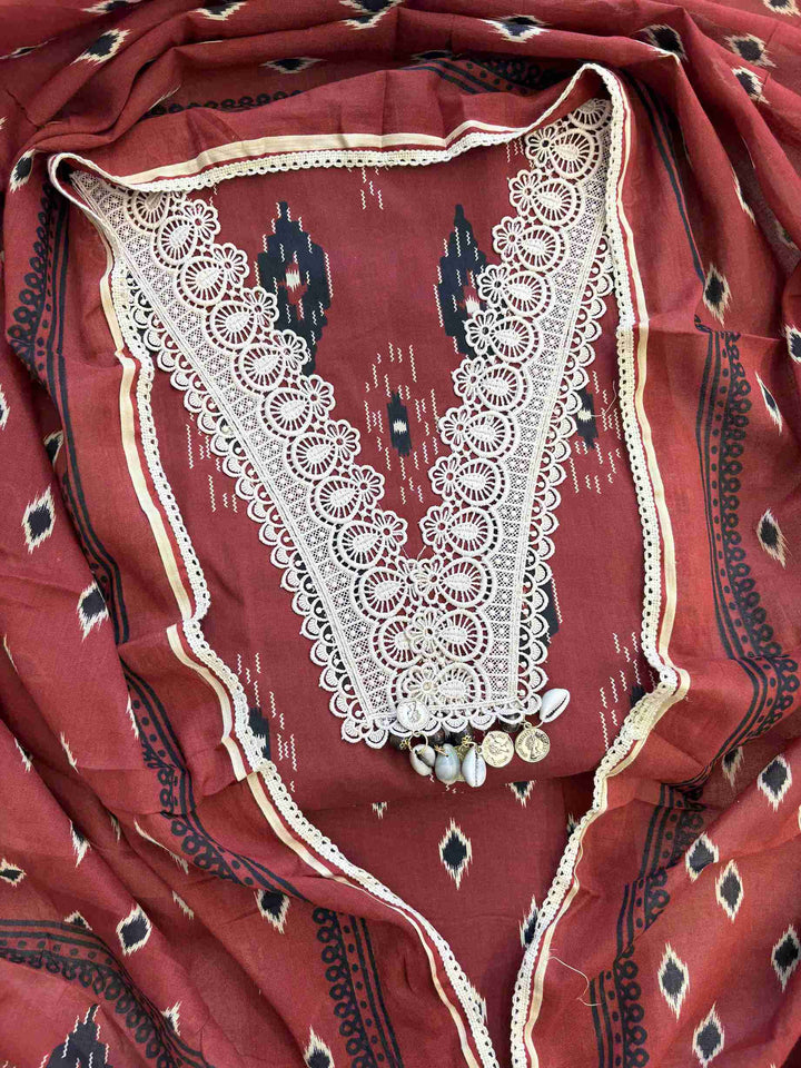 Close-up of all-over ikat-style diamond geometric print in black and cream tones on brick red cotton shirt body