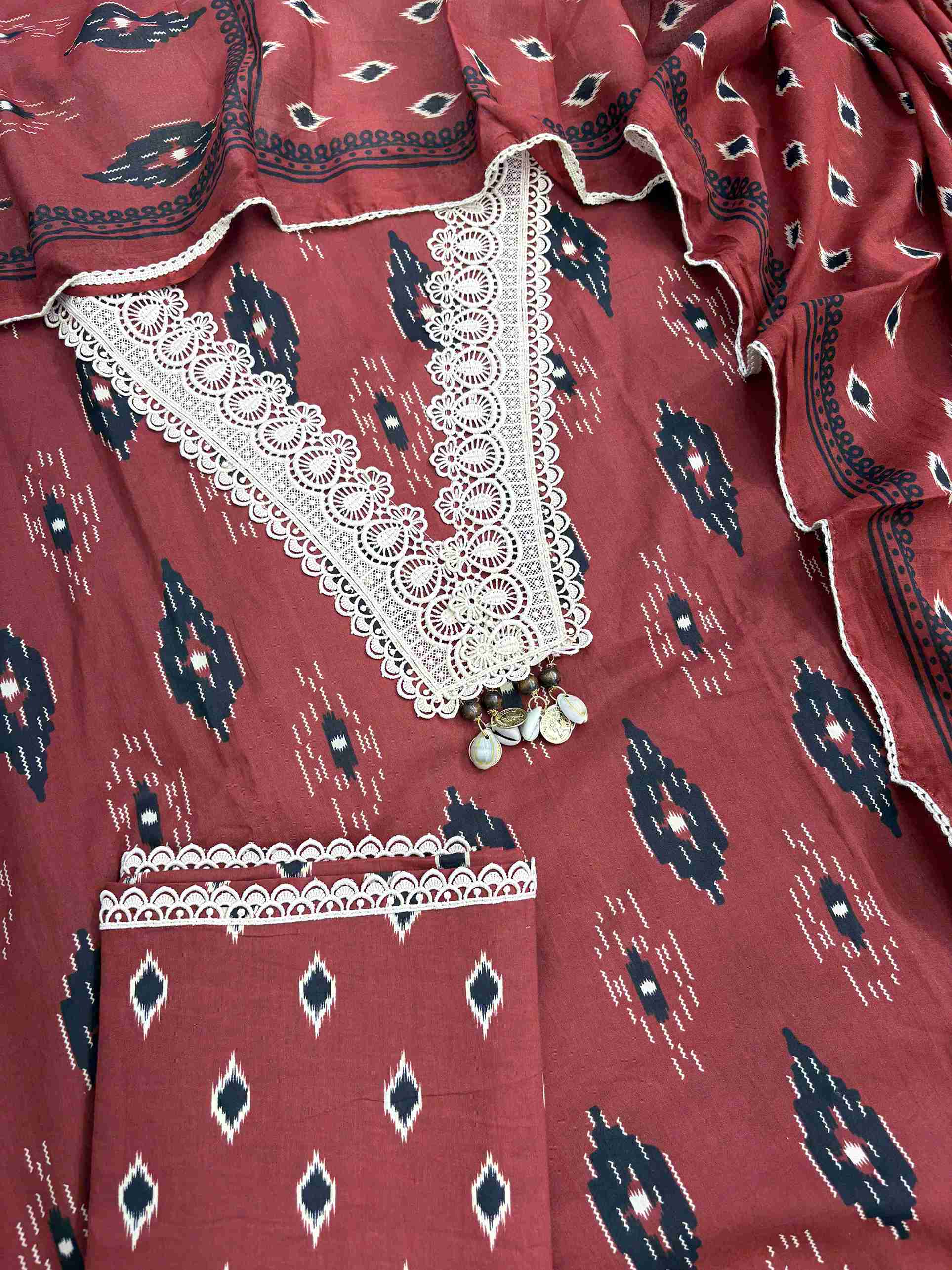 Complete brick red cotton unstitched suit flat lay set with ikat printed shirt, dupatta, and matching cotton bottom