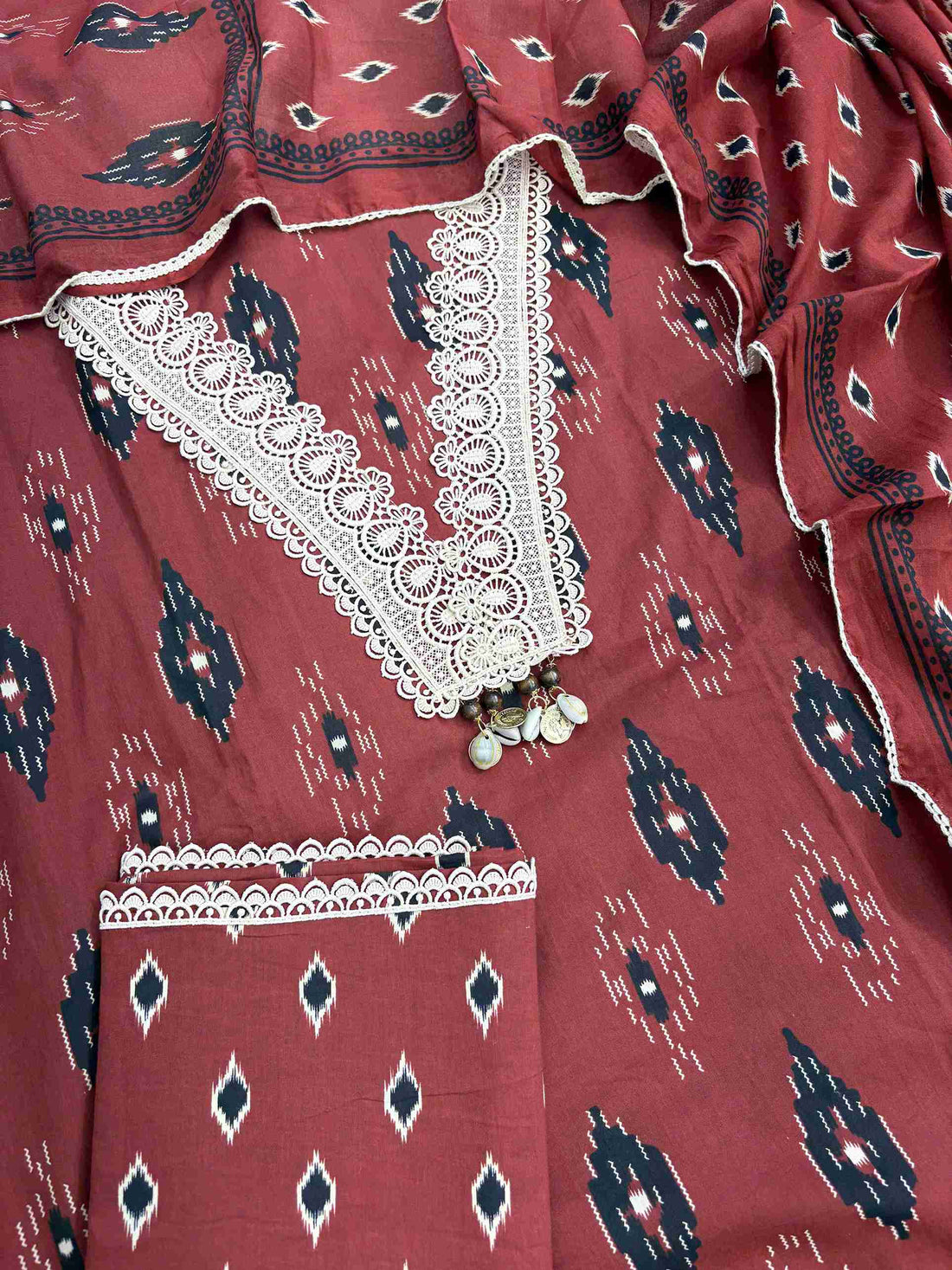 Complete brick red cotton unstitched suit flat lay set with ikat printed shirt, dupatta, and matching cotton bottom