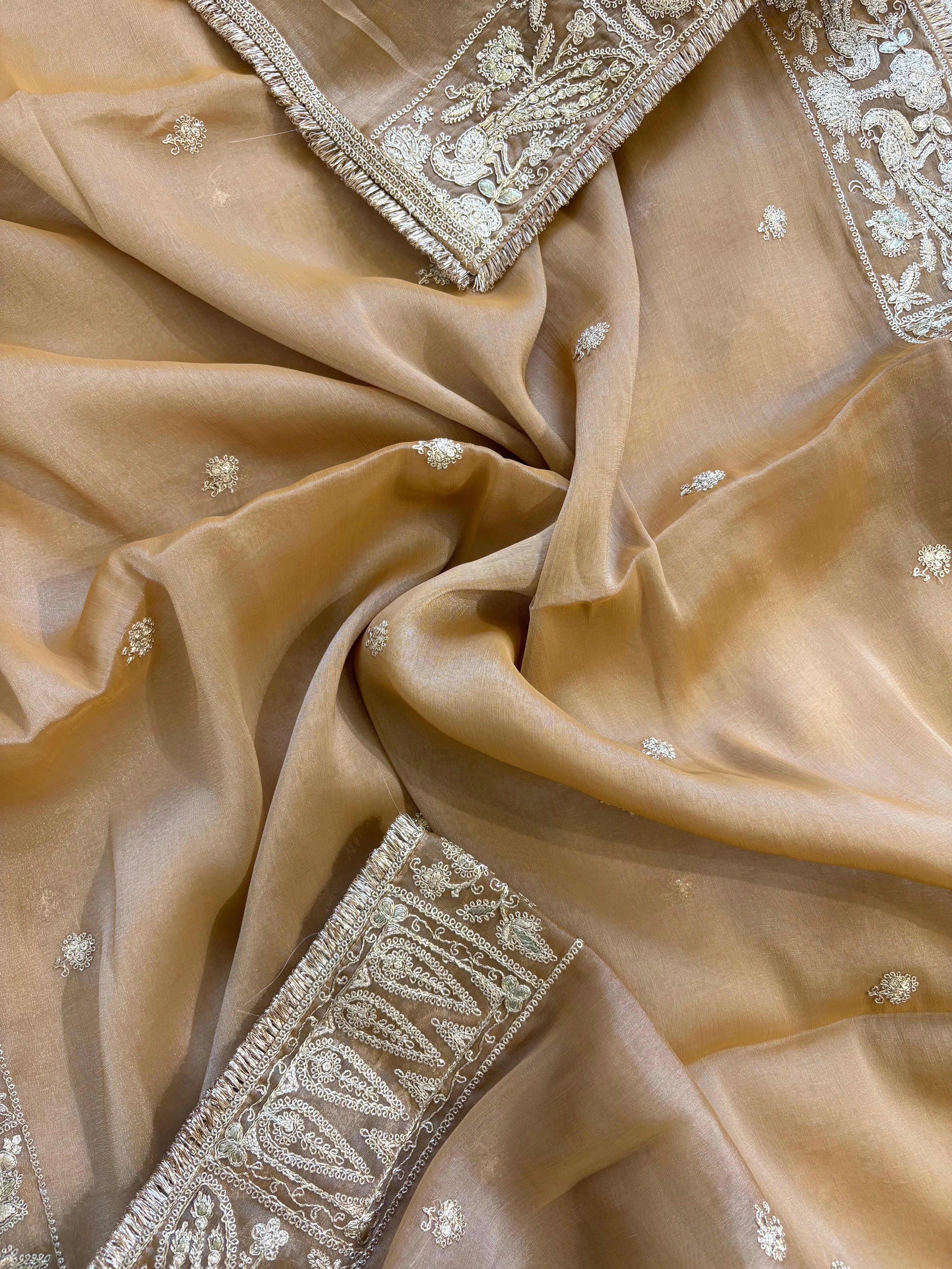 Beige organza unstitched suit with golden zari embroidery and embroidered dupatta, ideal for weddings and festive celebrations.