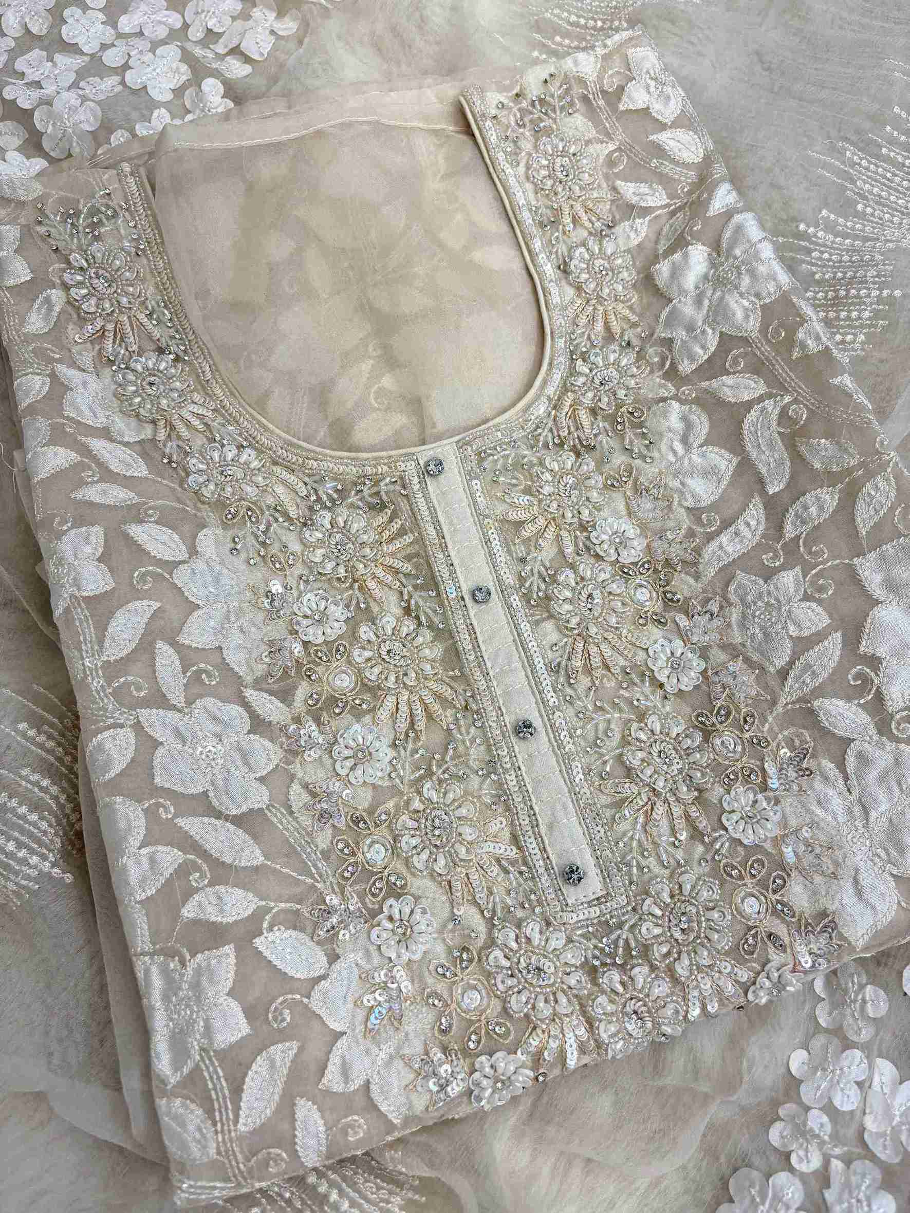 Close-up of all-over white floral applique work across the full body of champagne organza shirt