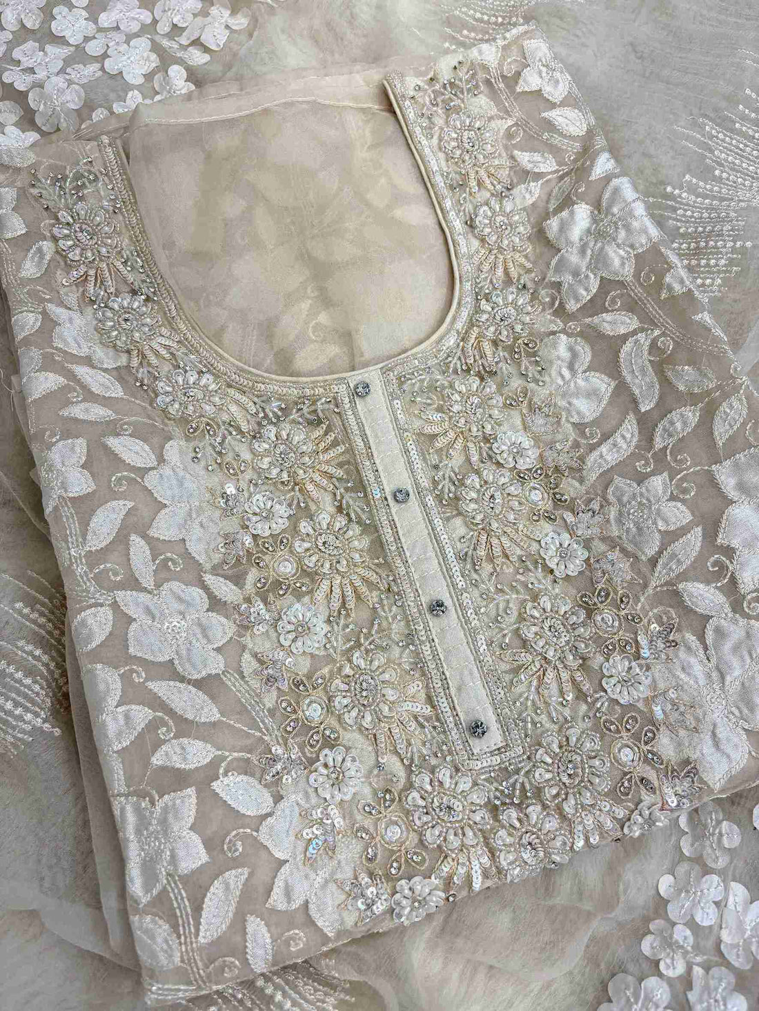 Close-up of all-over white floral applique work across the full body of champagne organza shirt