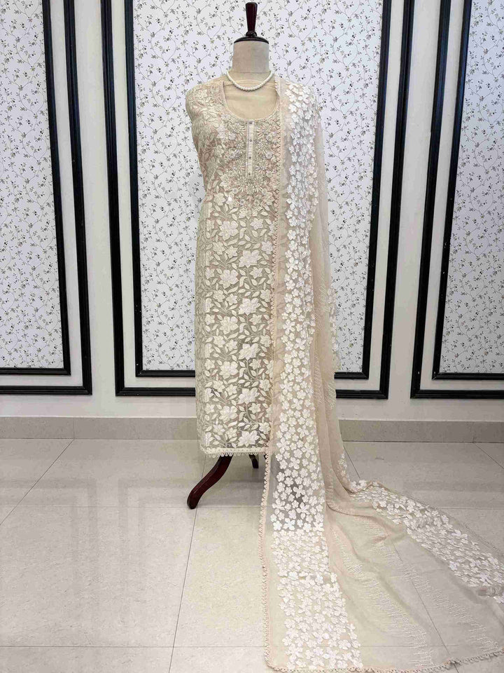 Champagne organza unstitched suit full front view with white floral applique and four-sided lace chiffon dupatta draped on mannequin