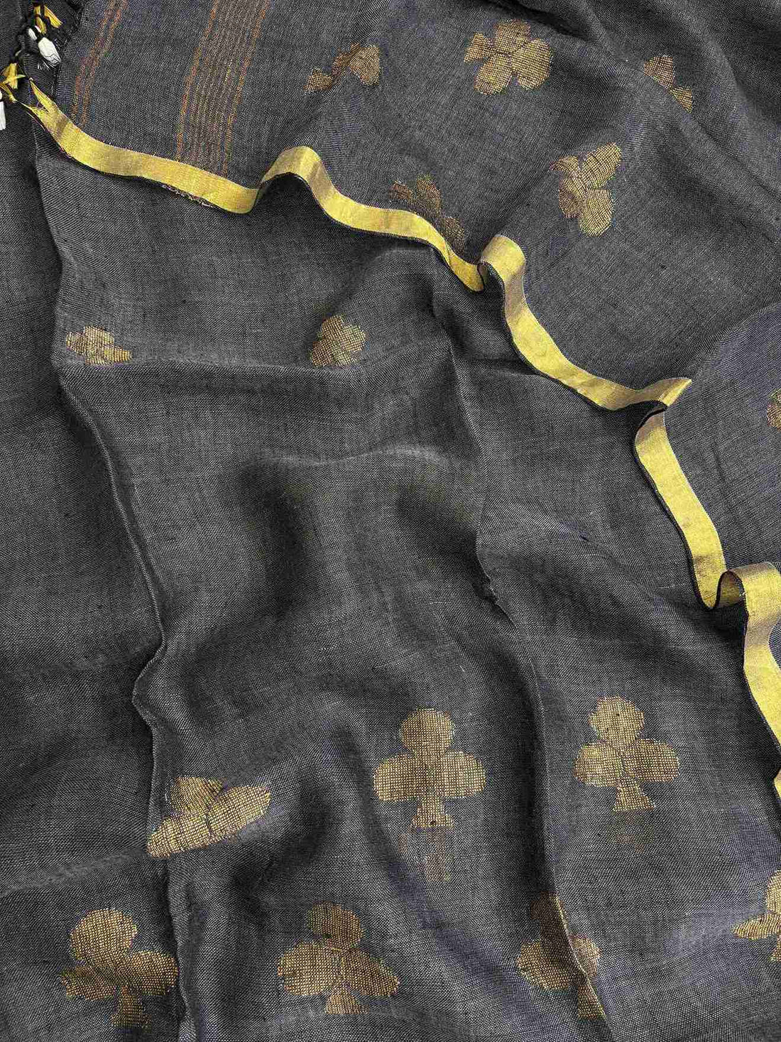 Scattered golden geometric spade woven motifs across charcoal grey pure handloom linen dupatta surface