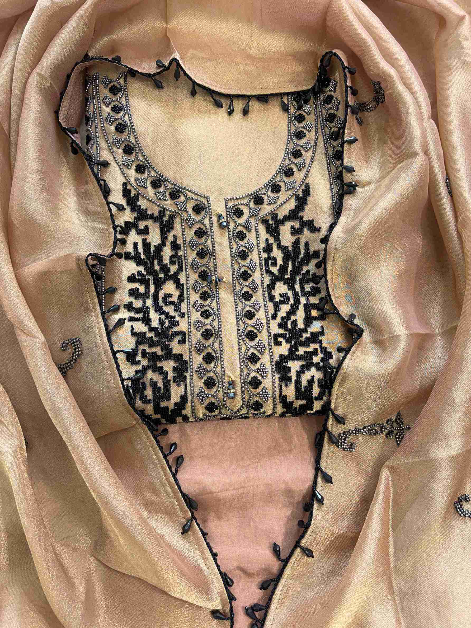 Close-up of black and silver cutdana and beads work on the neckline of copper beige giraffe tissue suit