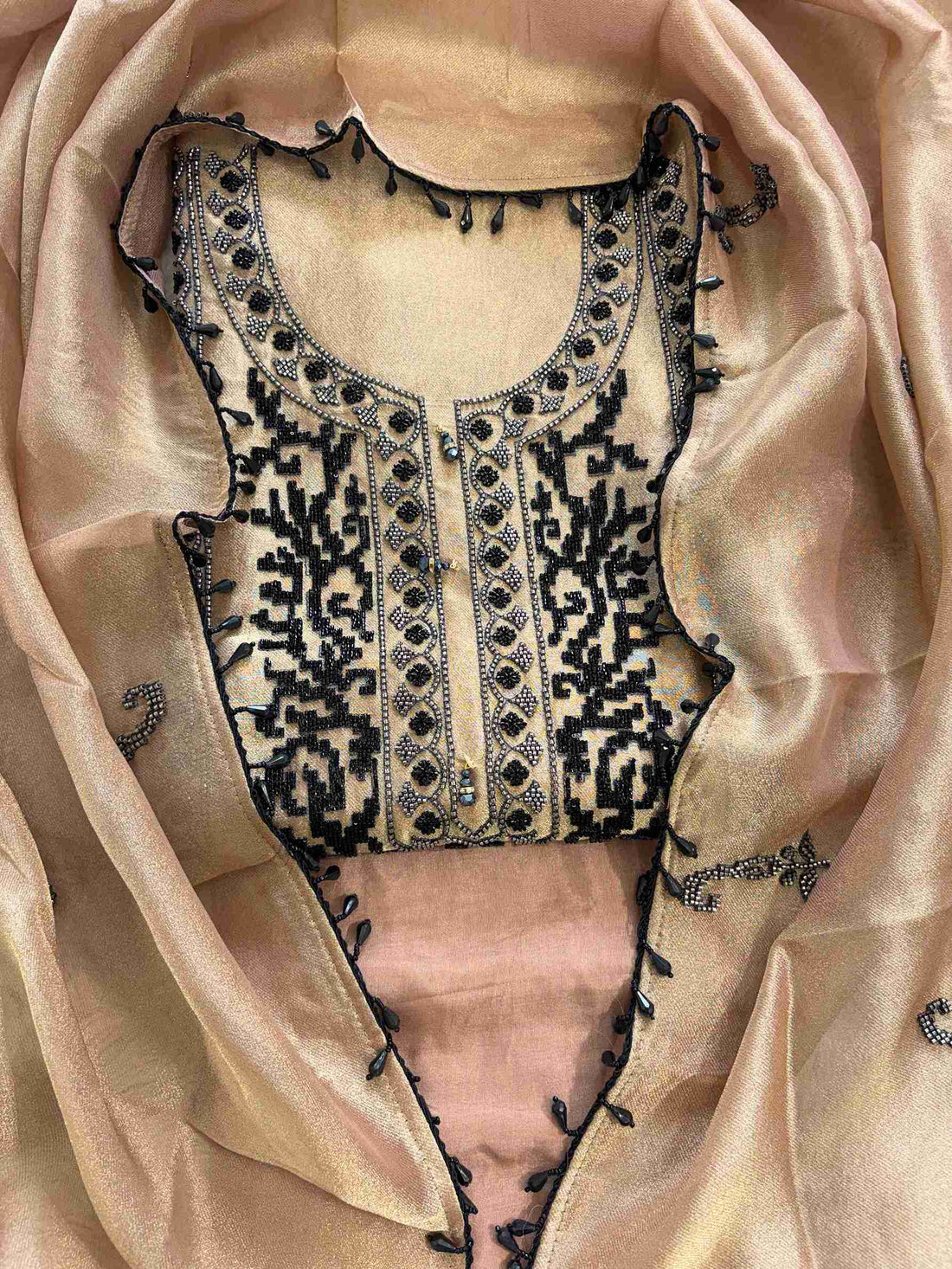 Close-up of black and silver cutdana and beads work on the neckline of copper beige giraffe tissue suit