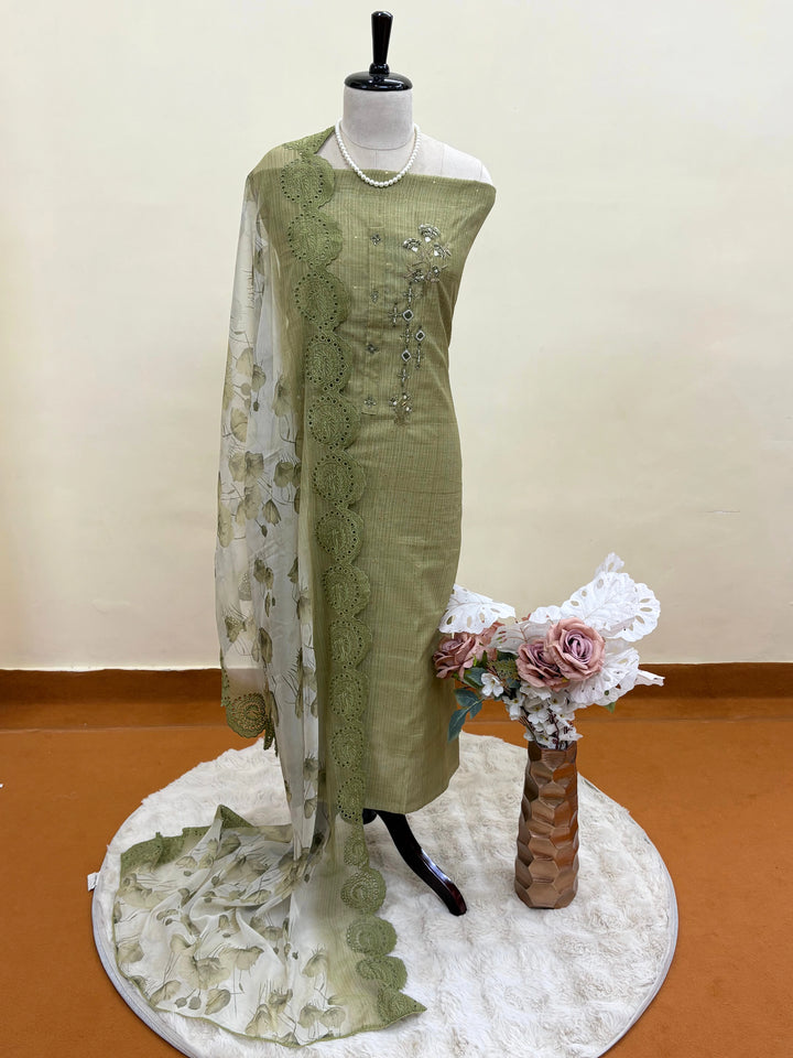 Olive green linen suit with floral threadwork, intricate lace detailing, paired with an organza dupatta with lace borders, ideal for weddings and special occasions.