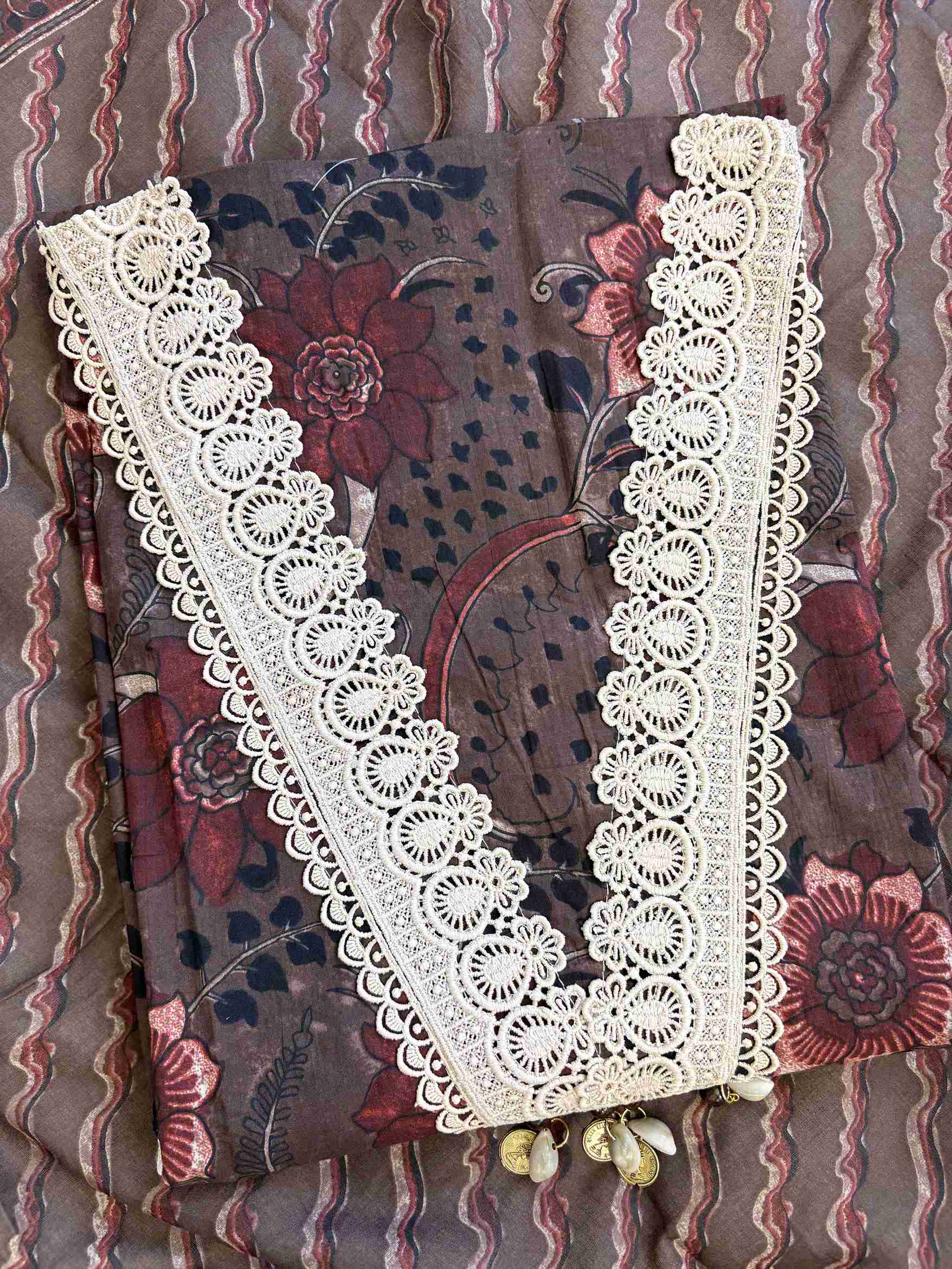 V-shaped neckline with broad crotia lace highlighting and decorative shell and coin tassels on dark chocolate brown cotton shirt