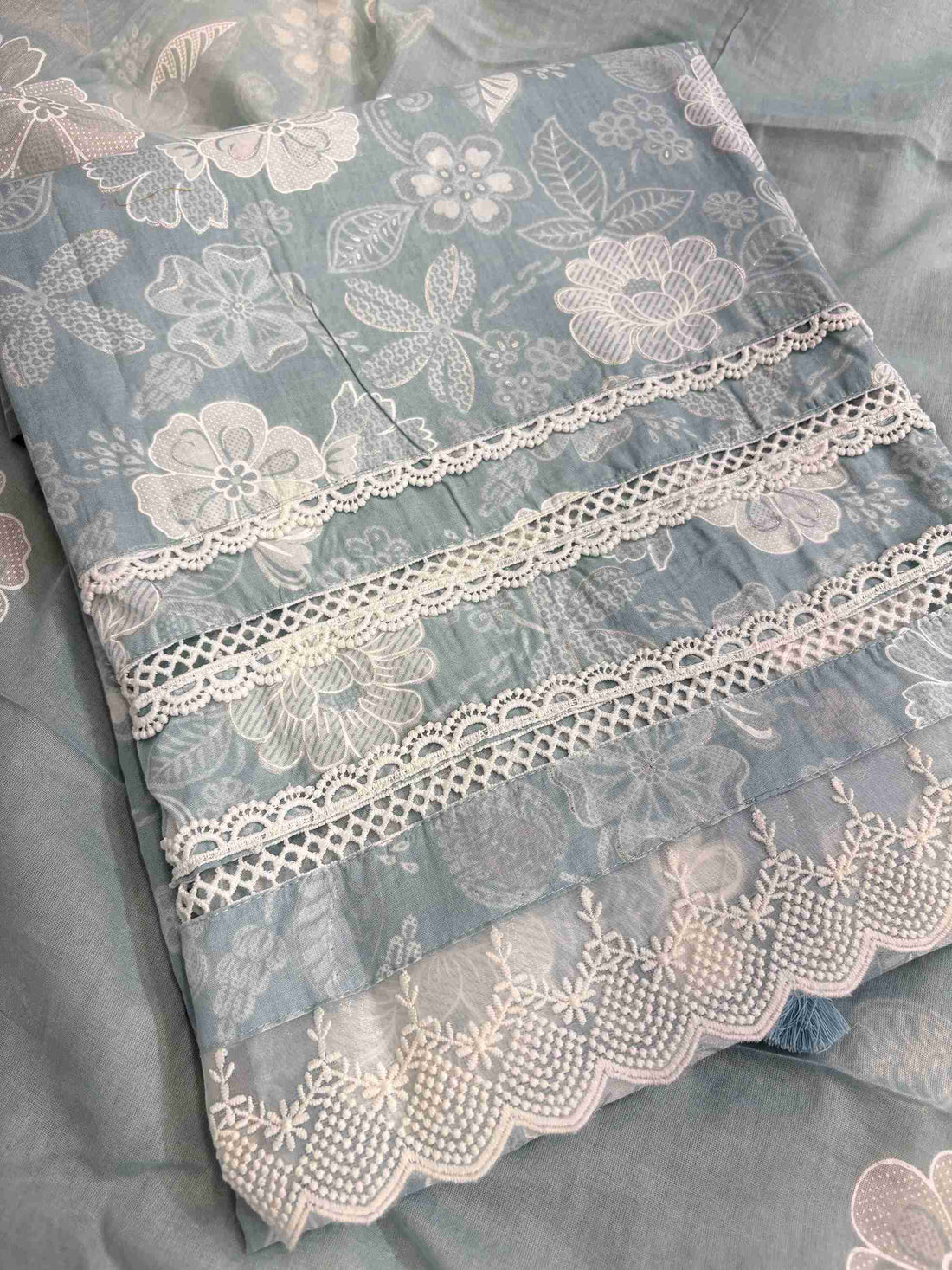 Multiple row crotia lace hemline finishing detail at the bottom of dusty blue cotton shirt