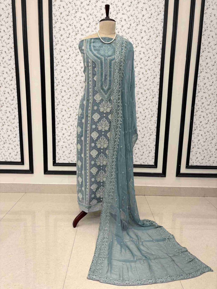 Dusty teal georgette unstitched suit displayed on mannequin with heavy embroidered neckline and chiffon dupatta