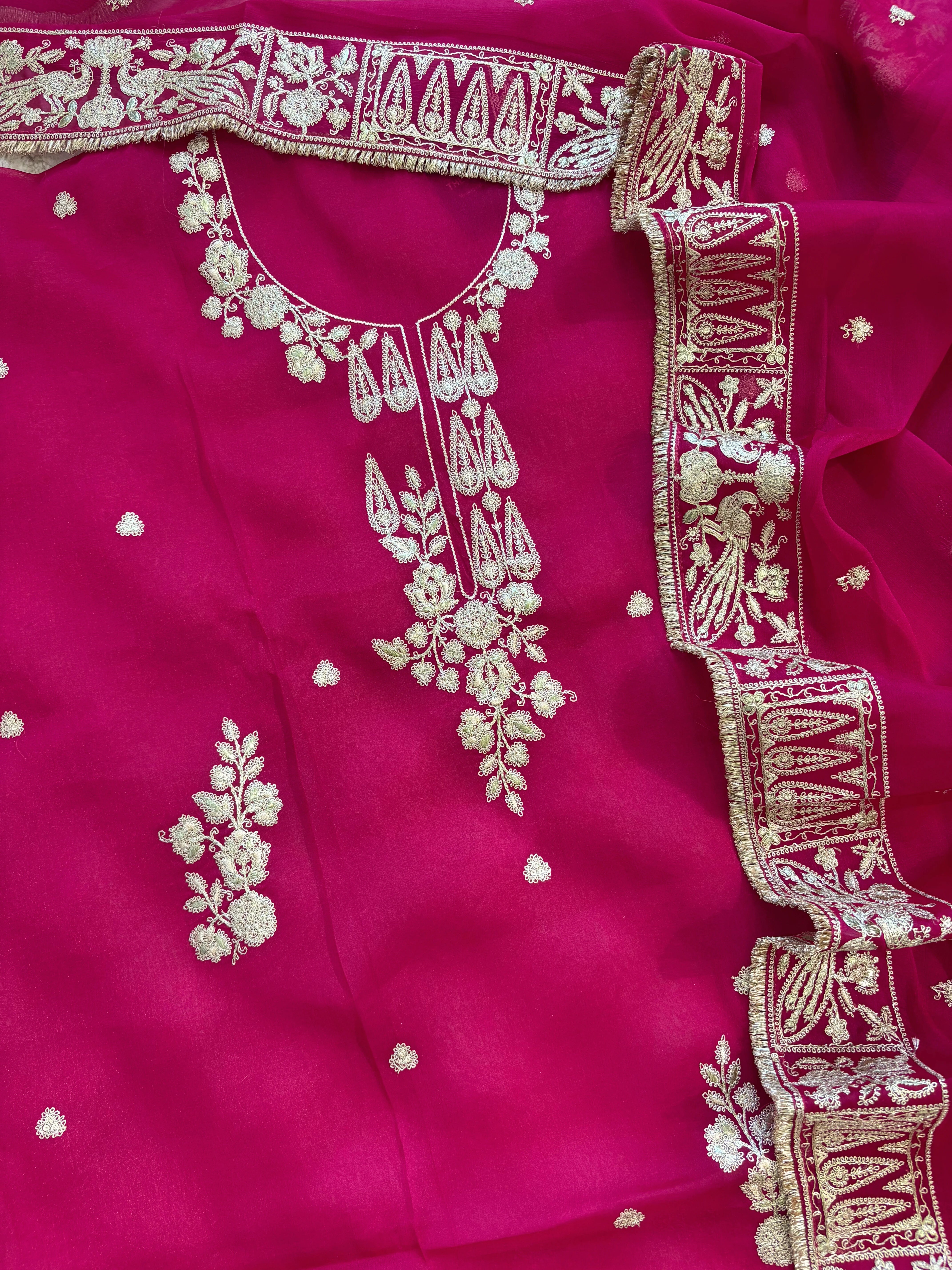 Hot pink organza unstitched suit with golden zari embroidery and embroidered dupatta, ideal for weddings and festive celebrations.