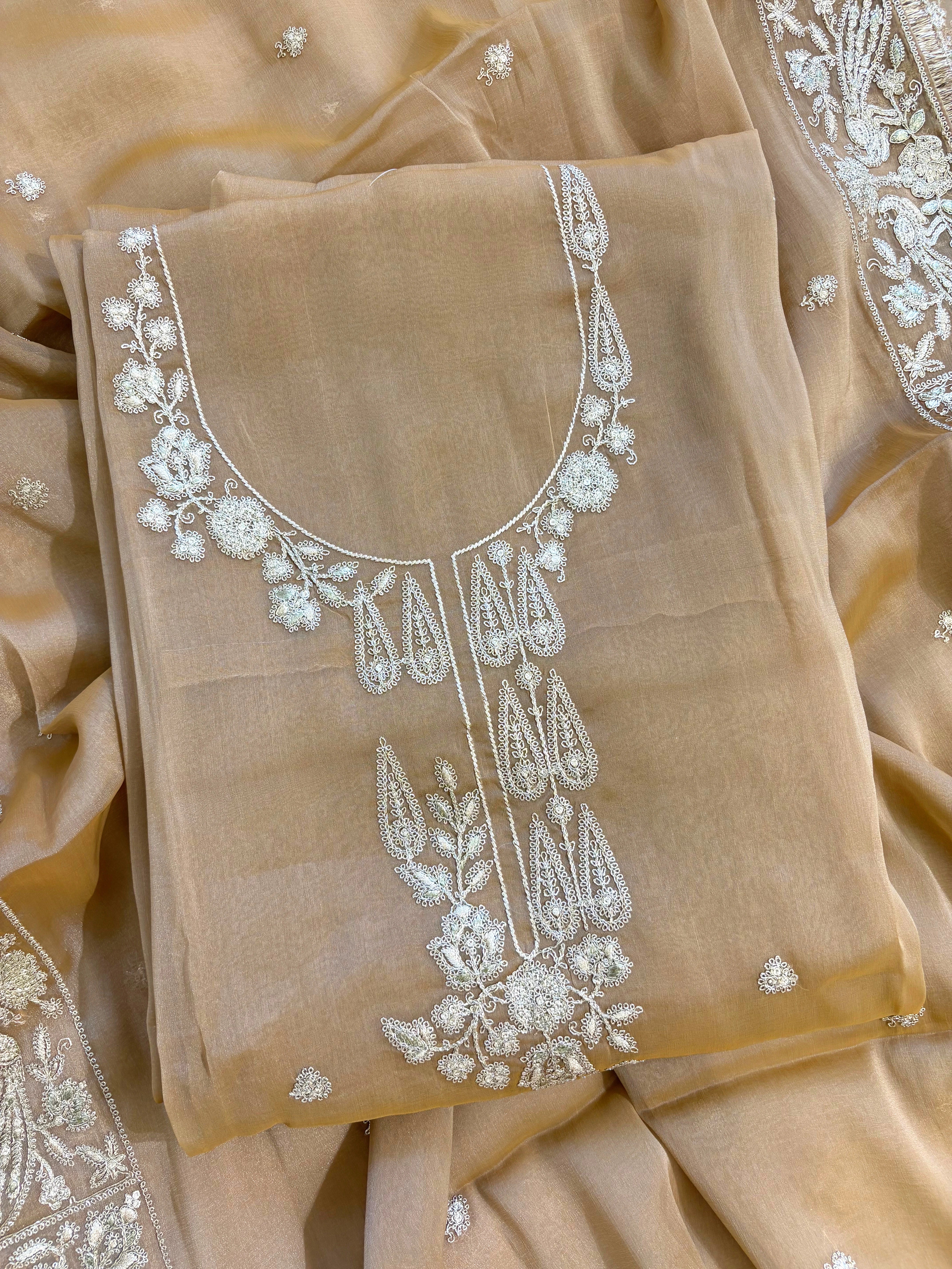 Beige organza unstitched suit with golden zari embroidery and embroidered dupatta, ideal for weddings and festive celebrations.