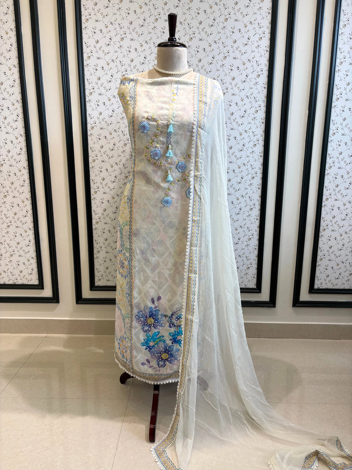 White cotton unstitched suit with embroidered neckline, lace detailing, and chiffon dupatta for summer festive wear.