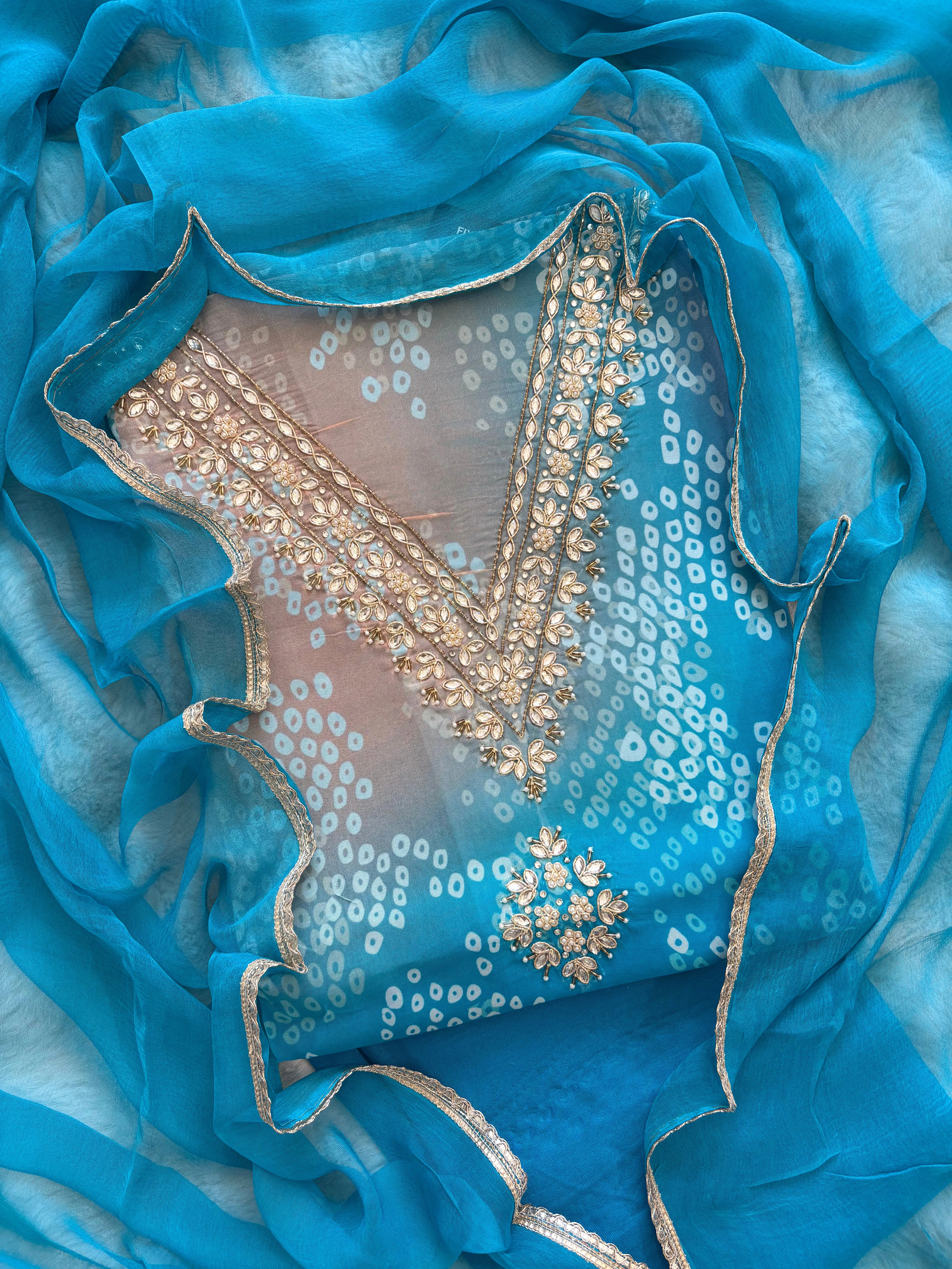 Blue organza bandhani suit with ombre effect and chiffon dupatta with lace border.
