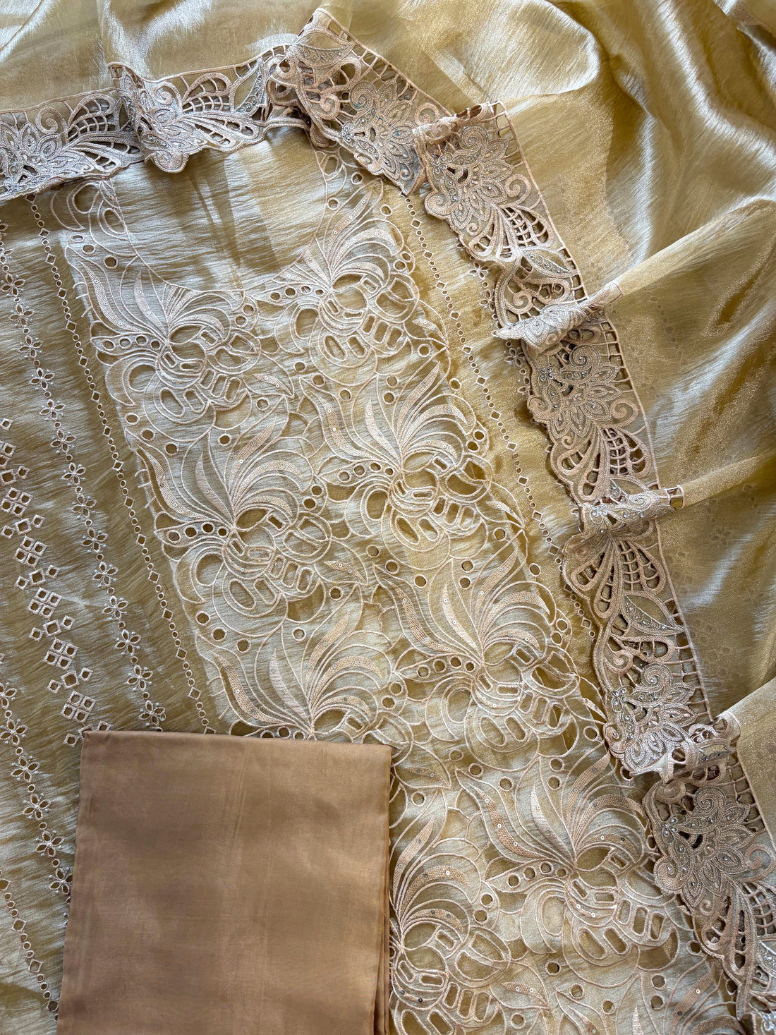 Close-up of cutwork panel at the neckline of gold-champagne-shimmer tissue suit