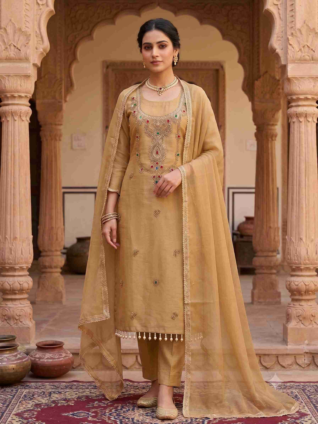 Model wearing golden beige simmar tissue unstitched suit with zardozi neckline
