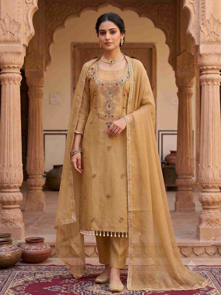 Model wearing golden beige simmar tissue unstitched suit with zardozi neckline