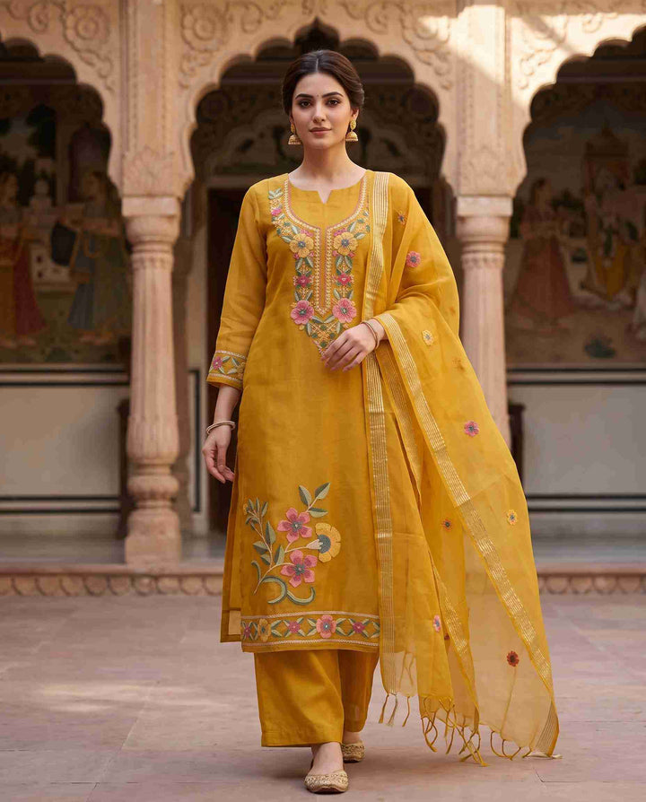 Model wearing golden yellow Chanderi unstitched suit with floral aari embroidery