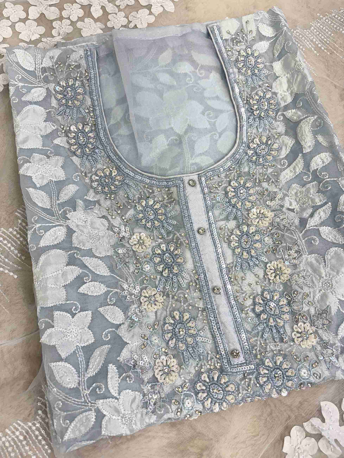 Close-up of all-over white floral applique work across the full body of ice blue organza shirt