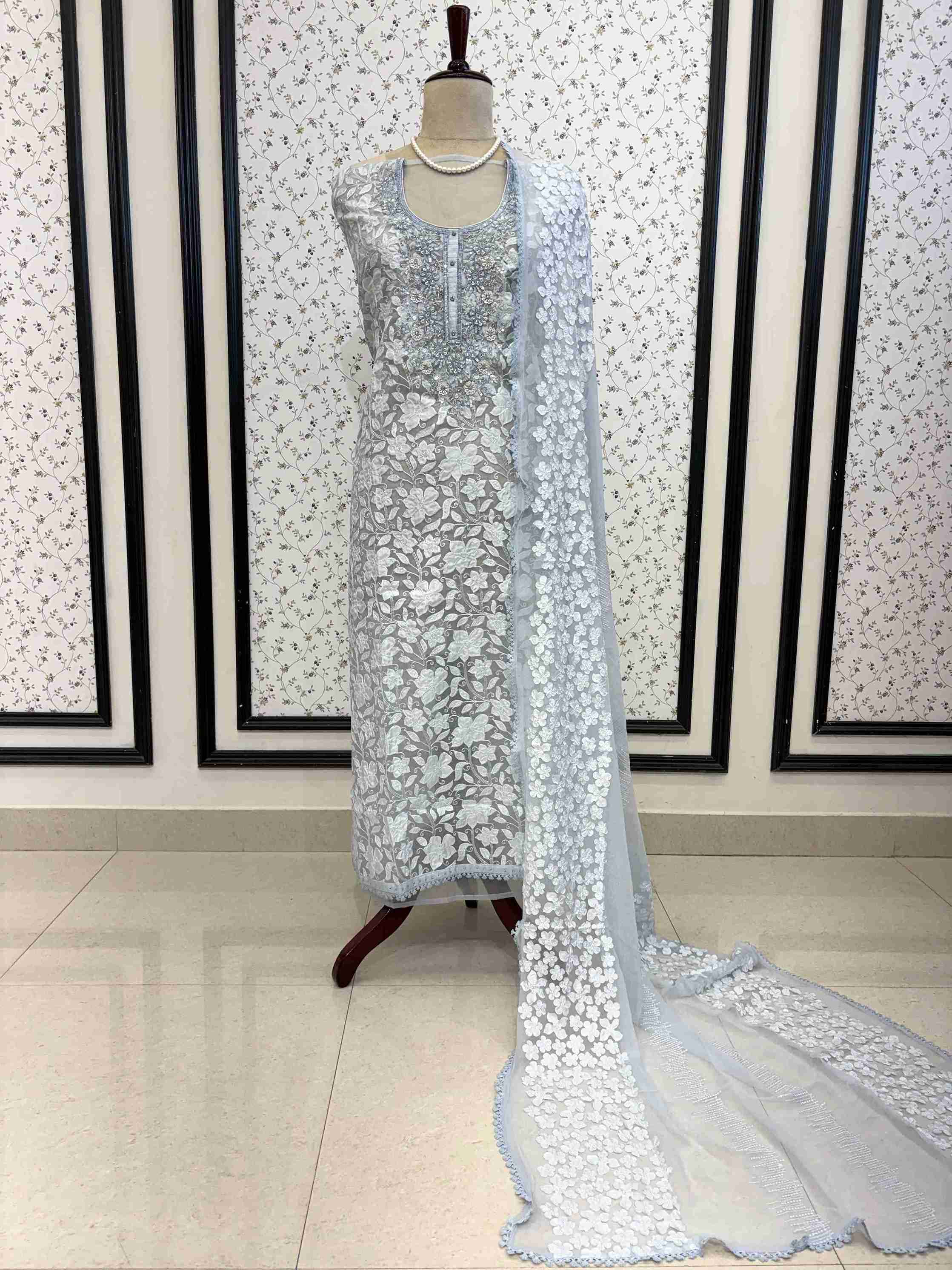 Ice blue organza unstitched suit full front view with white floral applique and four-sided lace chiffon dupatta draped on mannequin