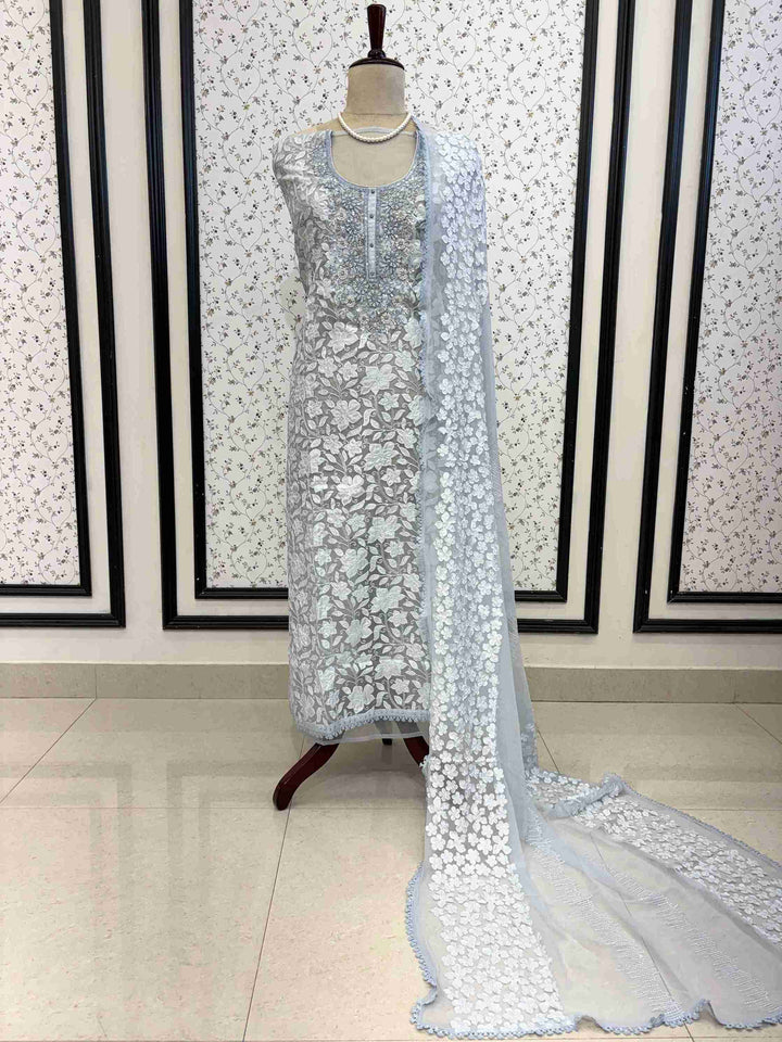 Ice blue organza unstitched suit full front view with white floral applique and four-sided lace chiffon dupatta draped on mannequin