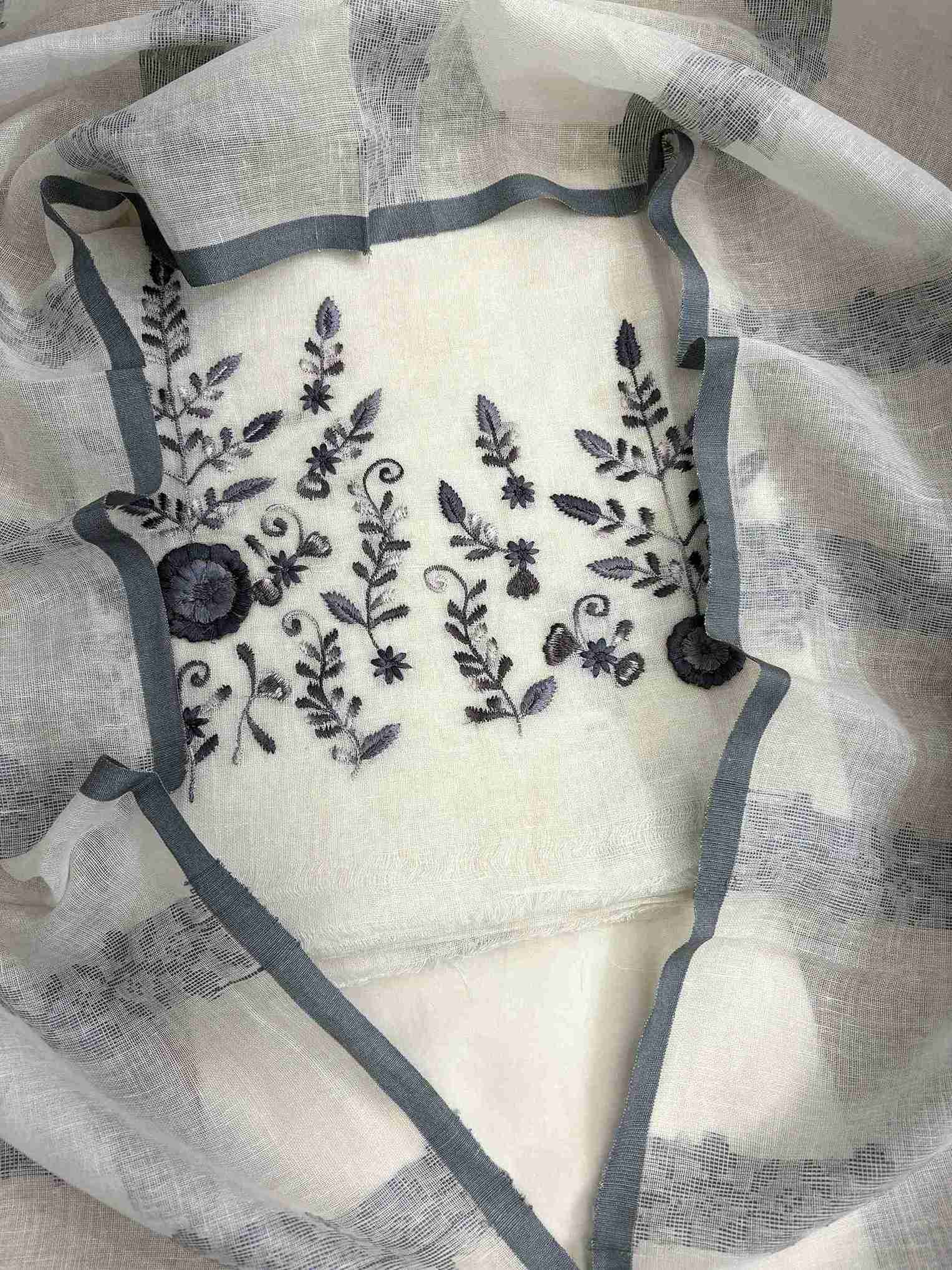 Close-up of contrasting thread embroidery with floral and botanical motifs on ivory linen shirt hemline