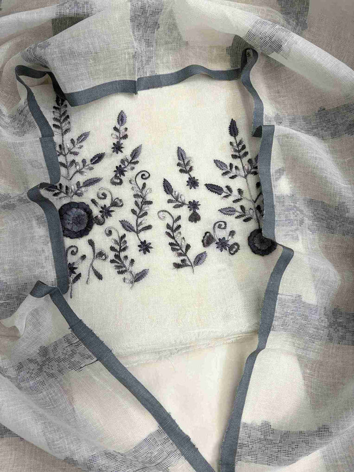 Close-up of contrasting thread embroidery with floral and botanical motifs on ivory linen shirt hemline