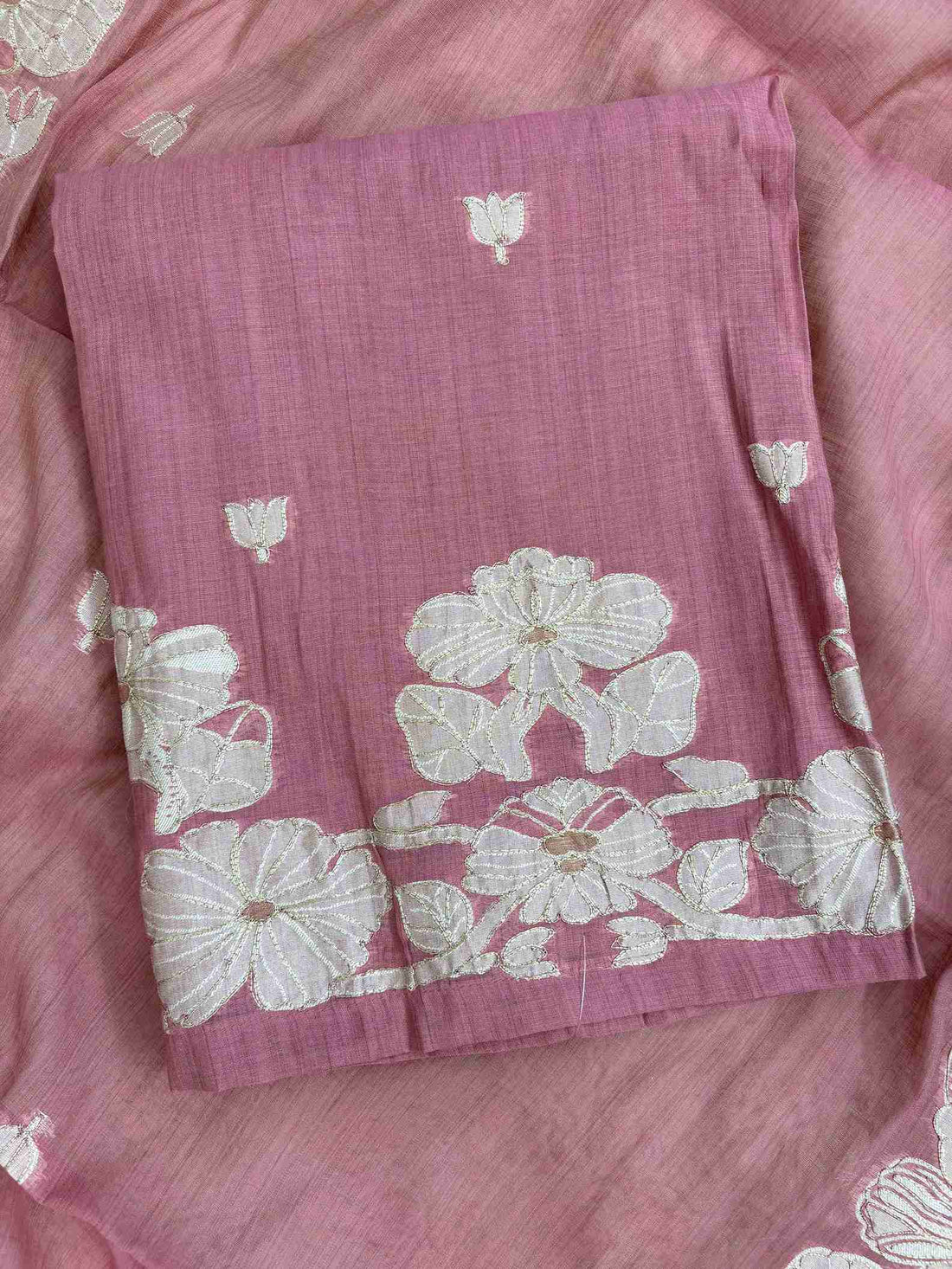 Close-up of woven floral vine hemline with golden thread highlights on mauve pink suit